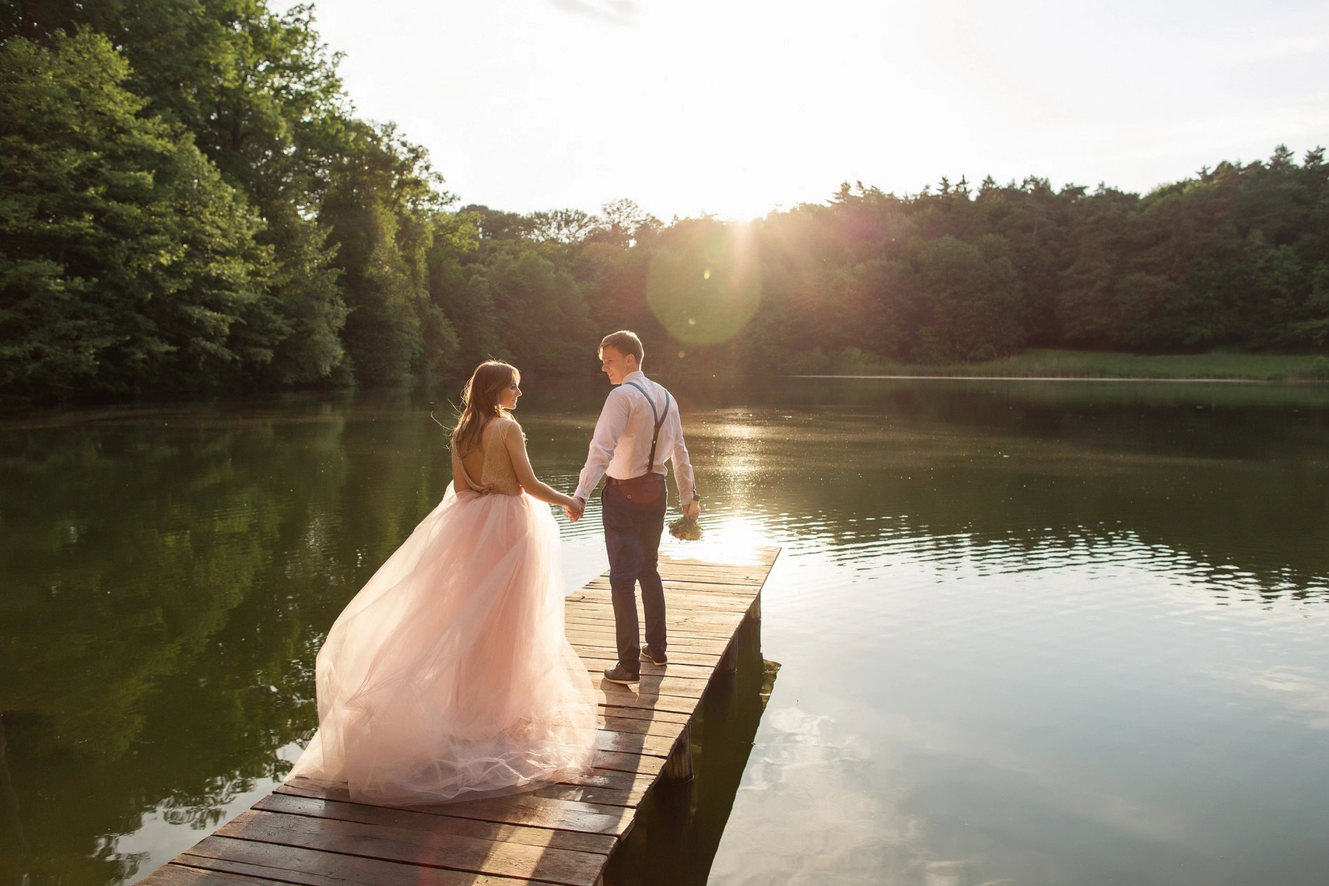 Bride standing by the lake at Martin's Château du Lac, surrounded by sunset light.