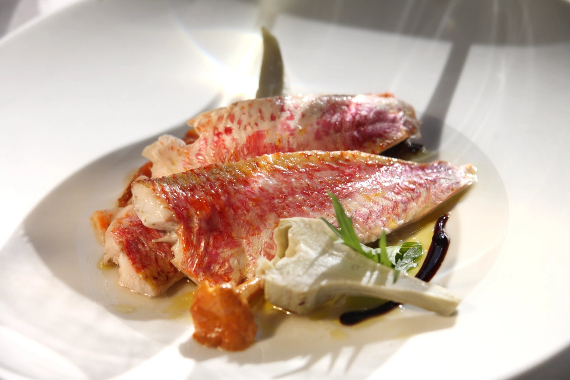 Plat de poisson entier avec accompagnement, symbolisant une spécialité de fruits de mer du restaurant de l'Hôtel La Ramade.