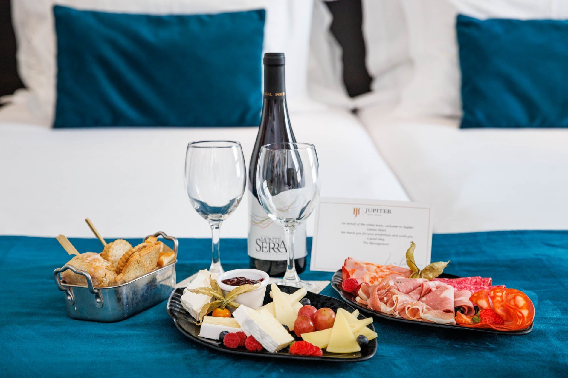 Conjunto de enchidos com dois copos de vinho numa cama do Jupiter Lisboa Hotel