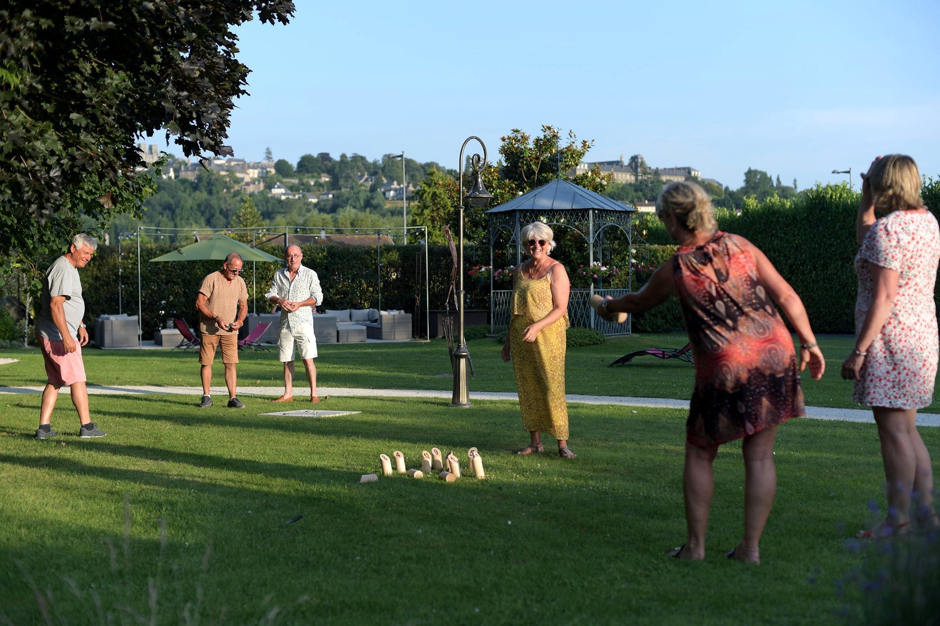 Clients jouant à la pétanque sur la pelouse de l'Hôtel La Ramade, symbolisant les activités de loisirs en plein air.