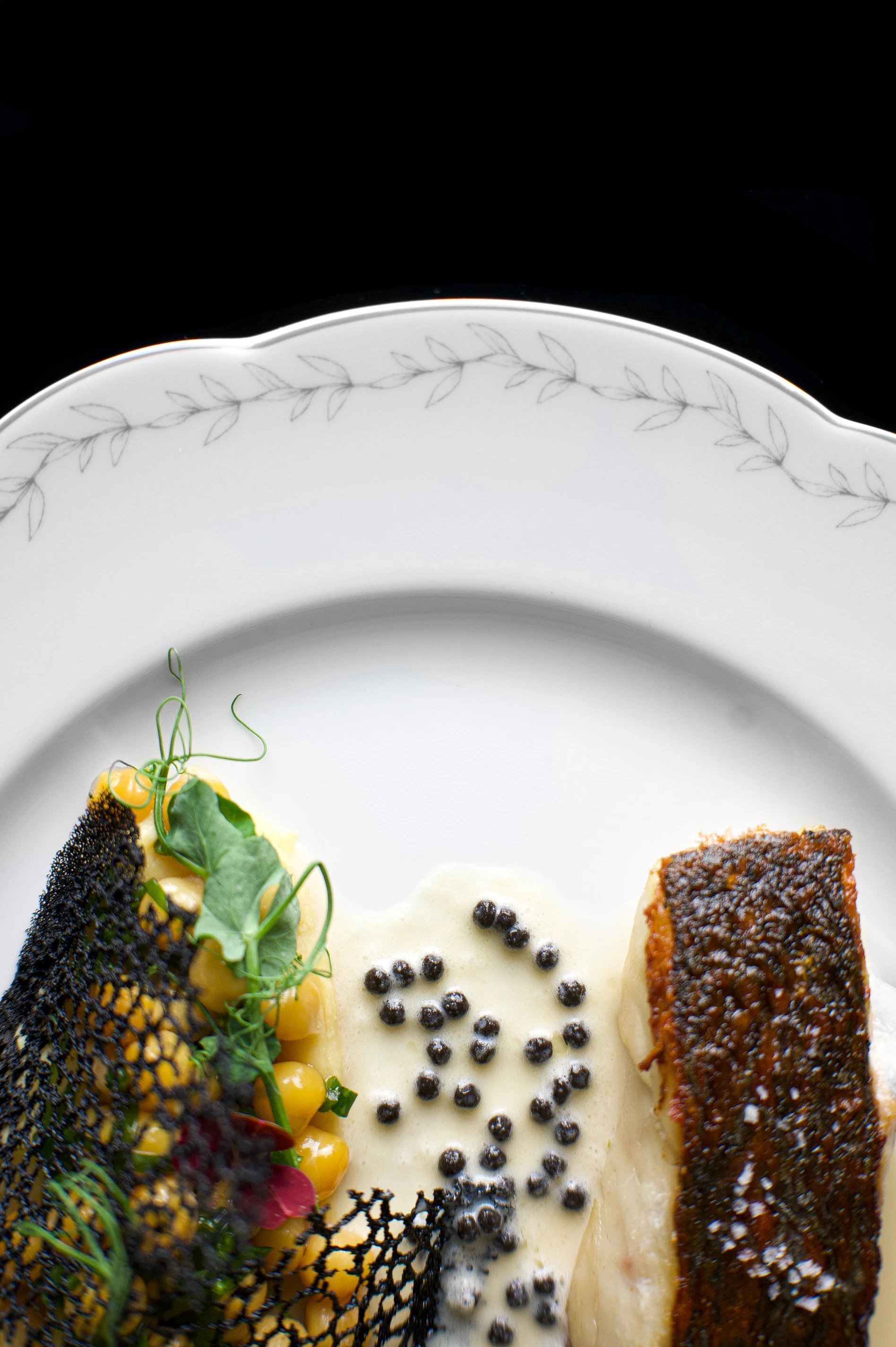 Assiette de poisson et garniture végétale délicate dressée avec précision à l’Hôtel San Régis.