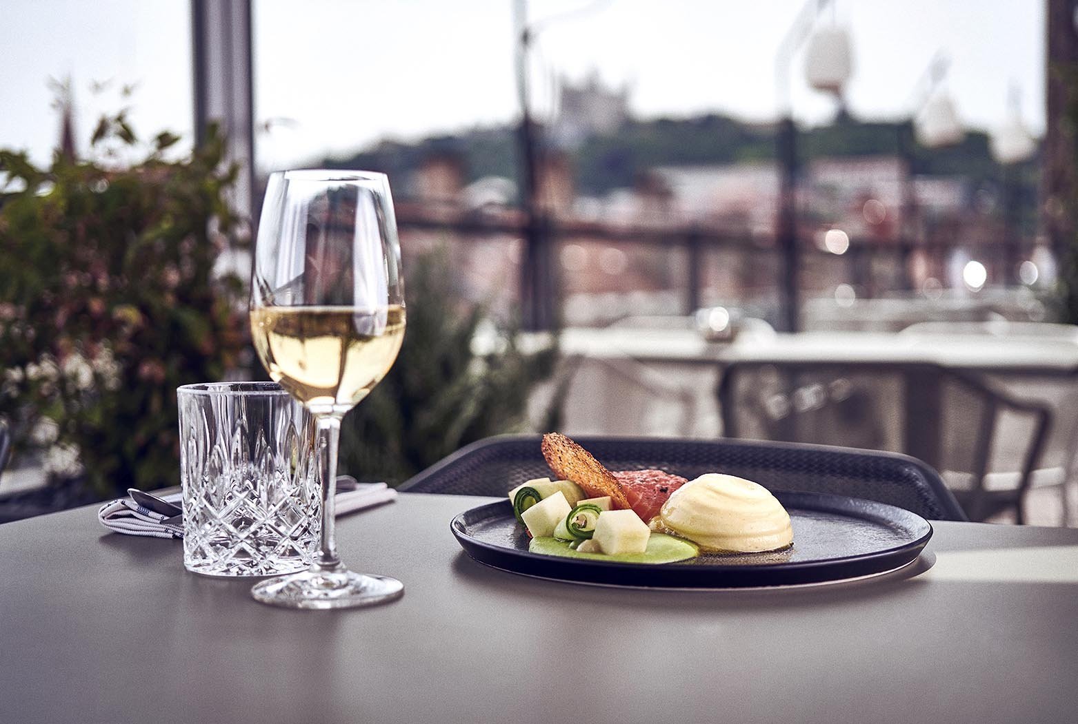 Plat et verre de vin blanc dressés sur une table de la terrasse du roof top Maison Nô Boutique hôtel Lyon