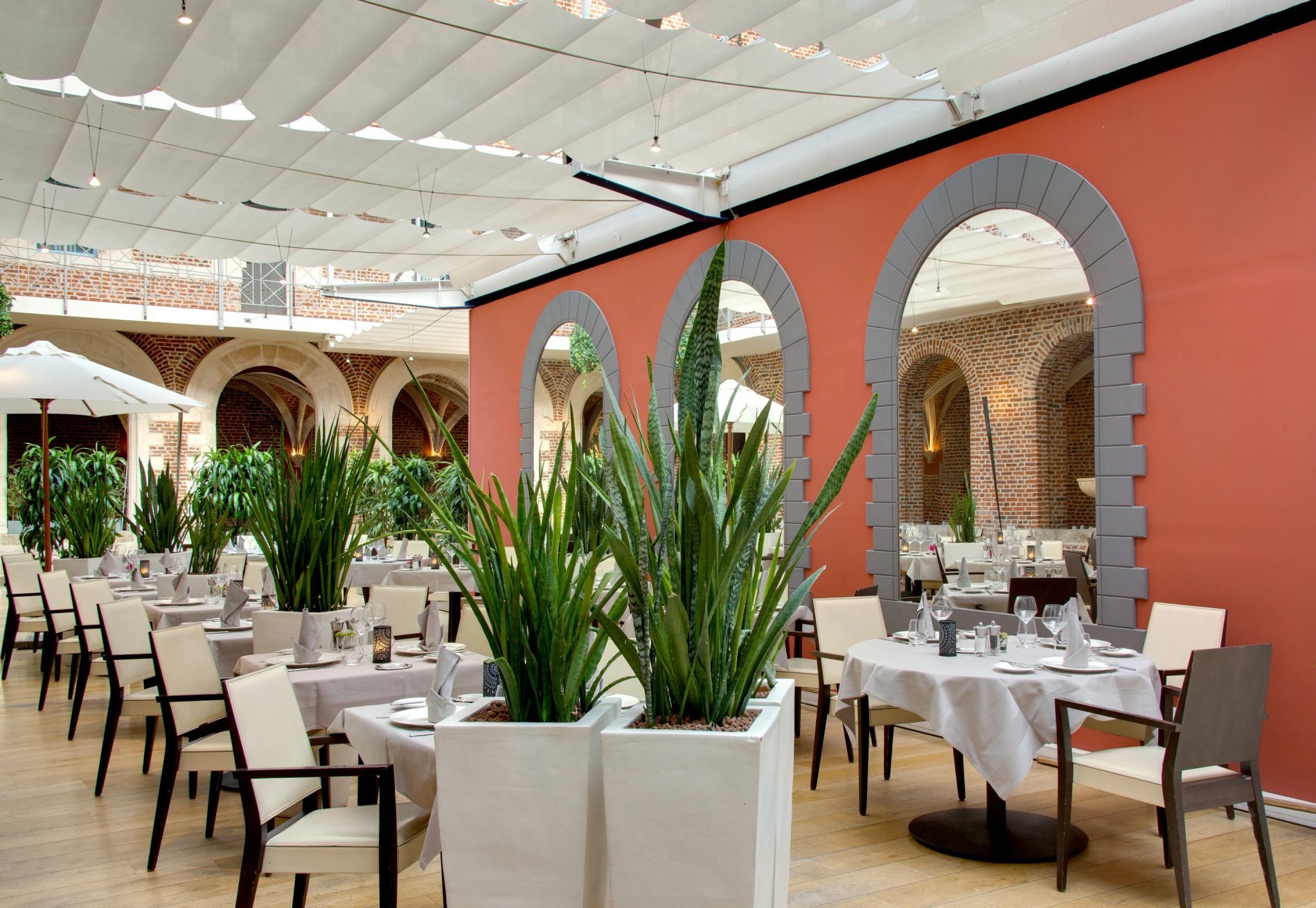 Hotel Le Couvent des Minimes in Lille showcases Le Jardin du Cloître, its elegant and spacious restaurant with large exposed brick arches.