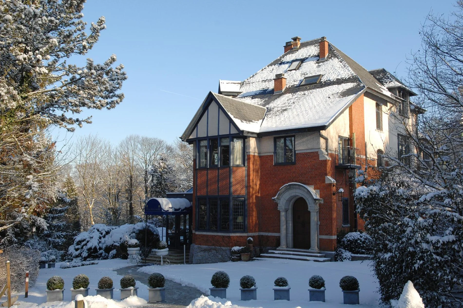 Façade enneigée du Manoir de Genval en hiver.