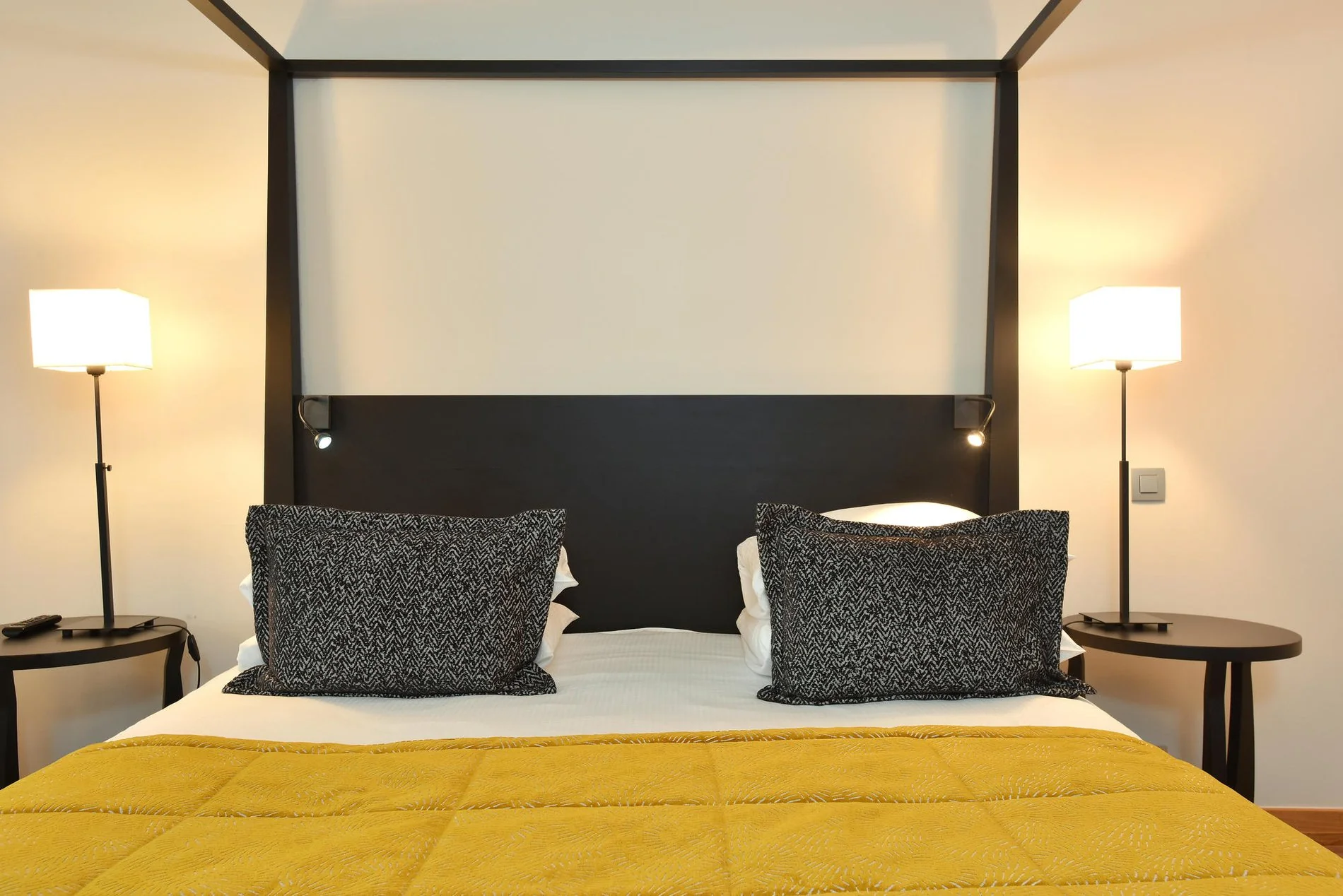 King bed met zwart hoofdeinde en gele sprei in de Great Lake View-kamer.
