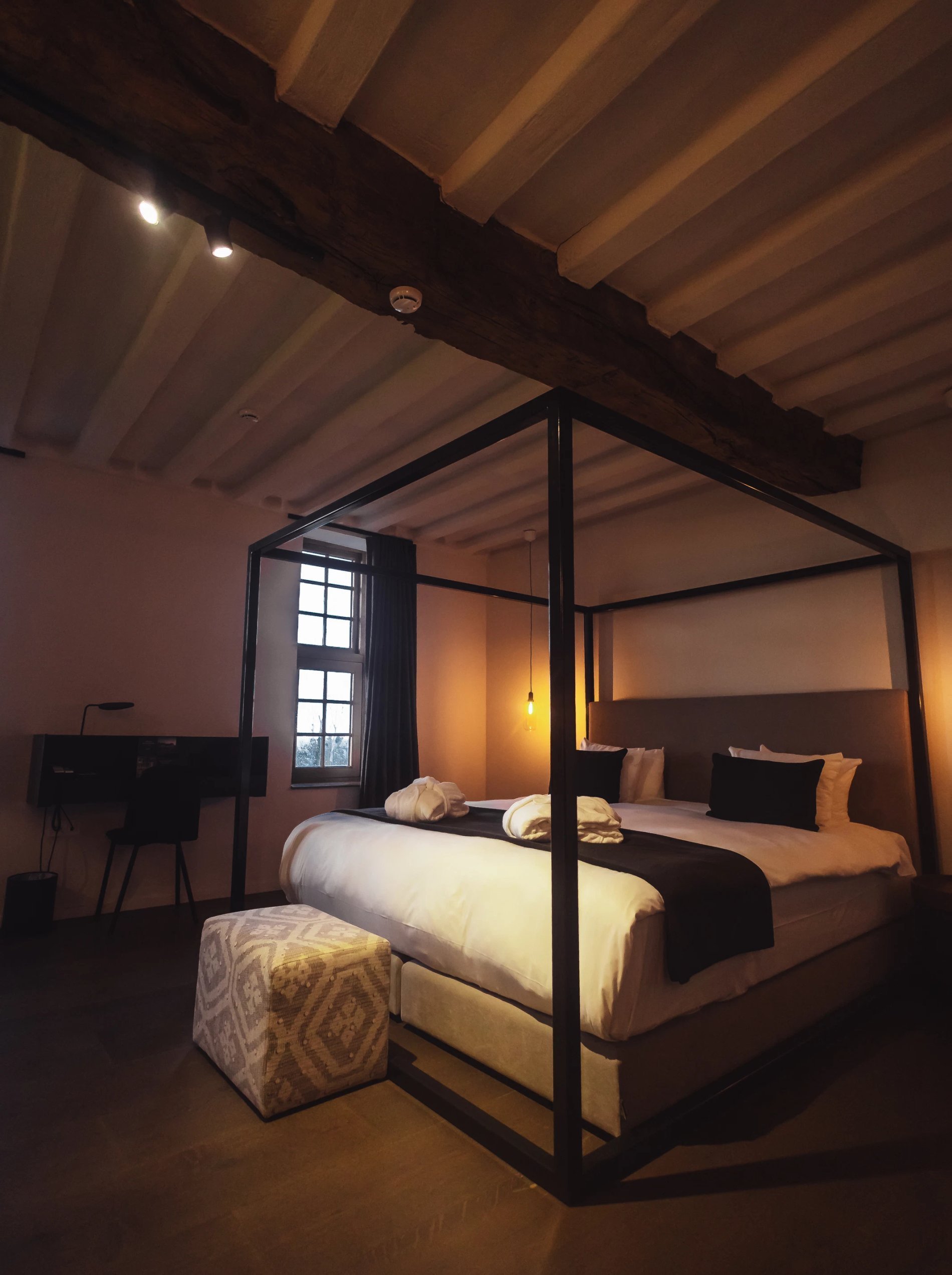 Chambre avec lit à baldaquin et poutres apparentes à l'hôtel Martin's Rentmeesterij, Bilzen.