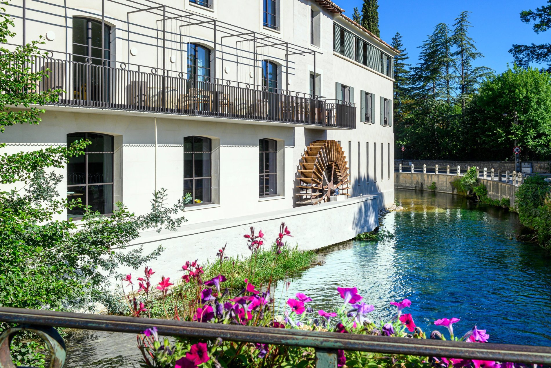 Vue extérieure du restaurant de l'Isle de Leos avec sa grande roue à aubes au bord de l’eau.