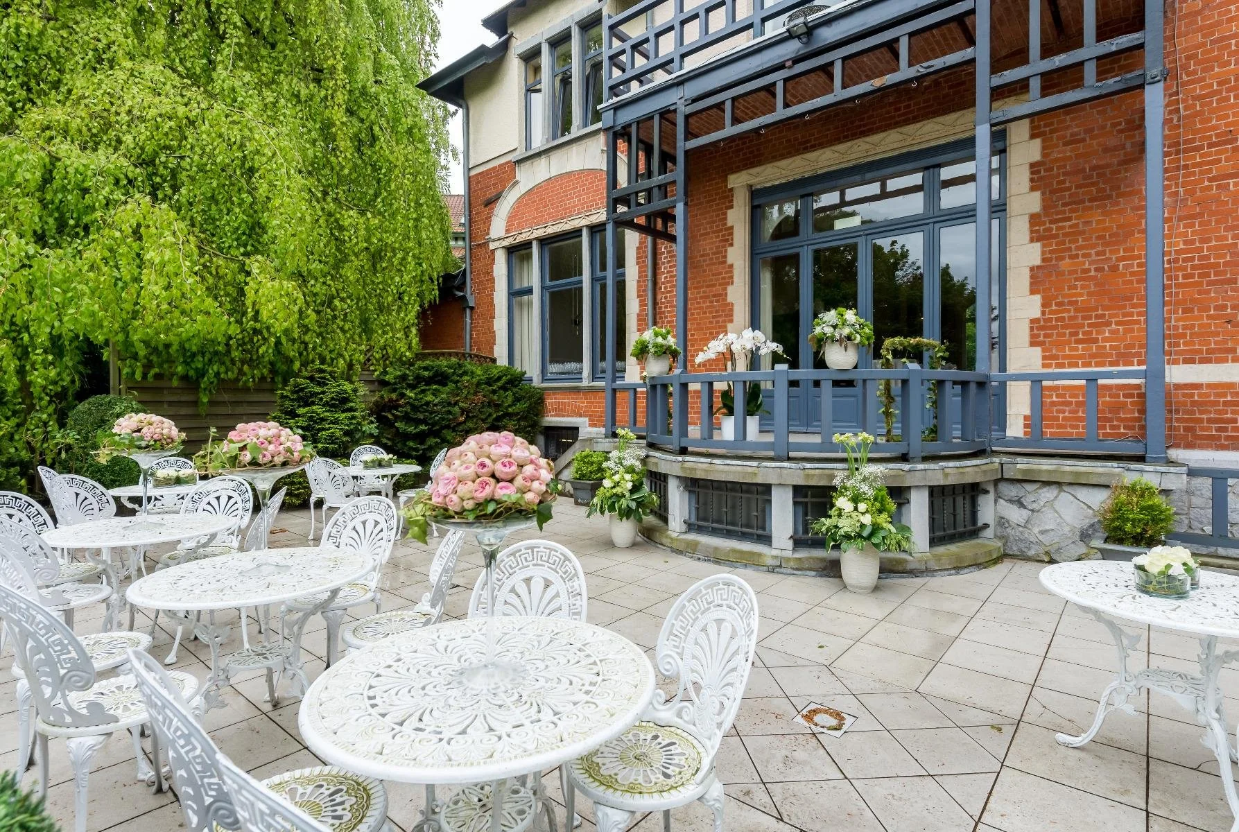 Terrasse élégante du Manoir de Genval entourée de verdure.