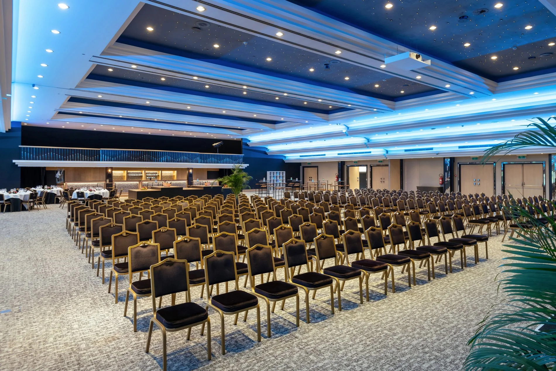 Salle de conférence spacieuse avec rangées de chaises et plafond illuminé de LED.