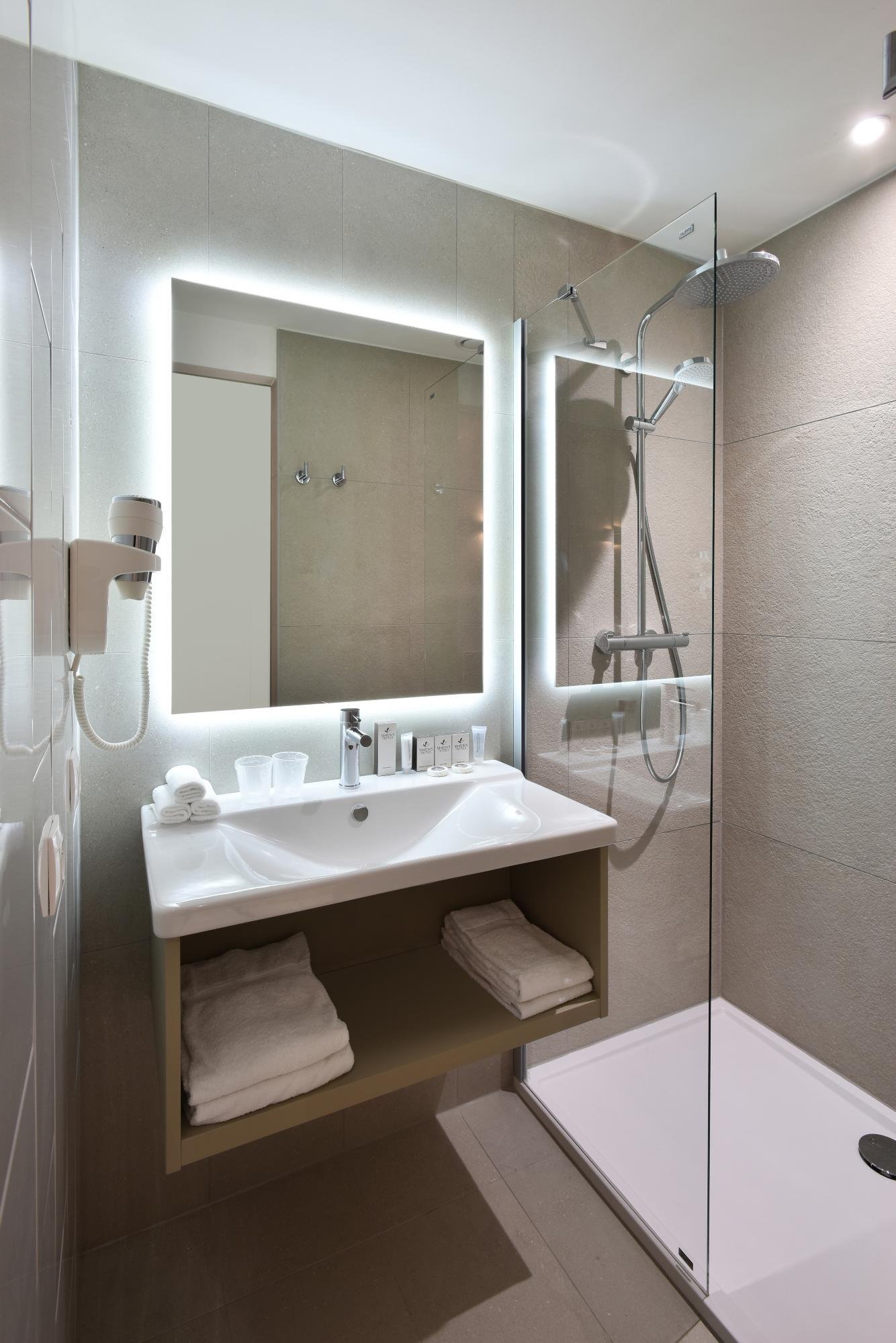 Heldere badkamer met douche en wastafel.