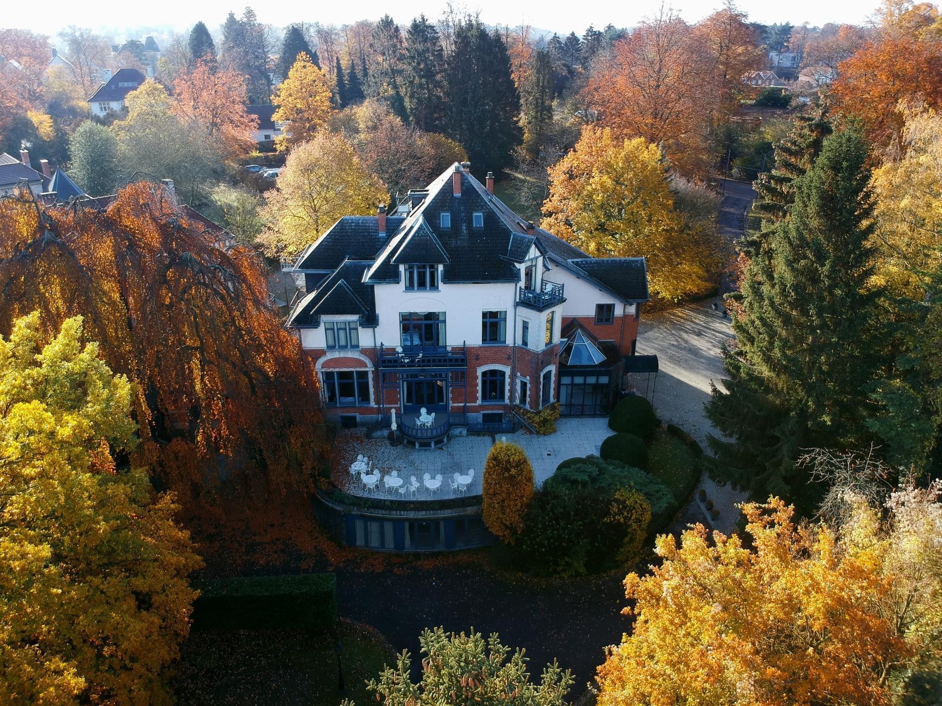 Vue aérienne du Manoir de Genval entouré des couleurs automnales.