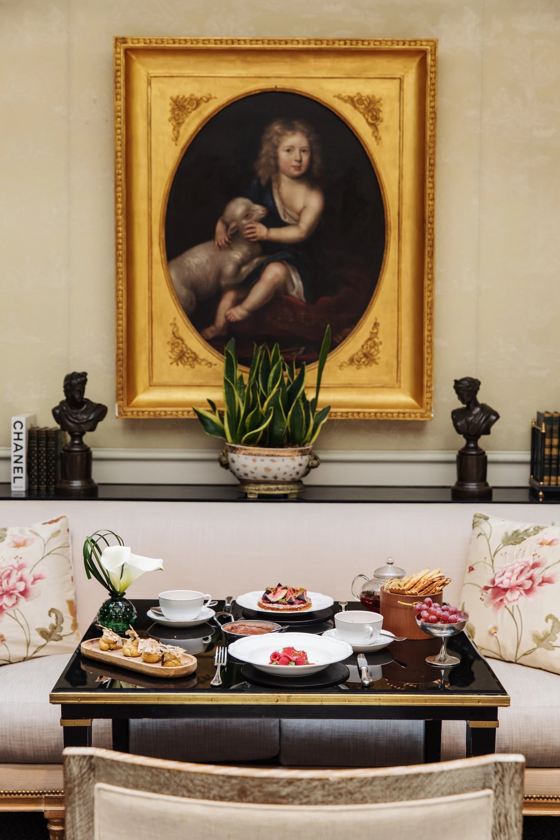 Table set for a French-style afternoon tea in the intimate lounge of Hôtel San Régis, beneath a classic portrait.
