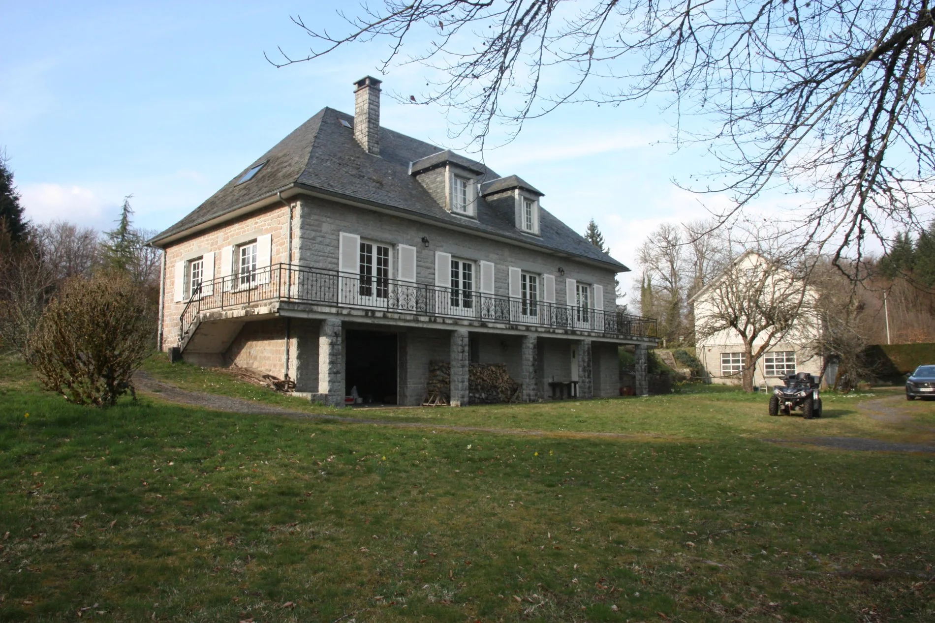Façade de Villa Corrèze Aventure avec grand jardin, garage ouvert et véhicule stationné.
