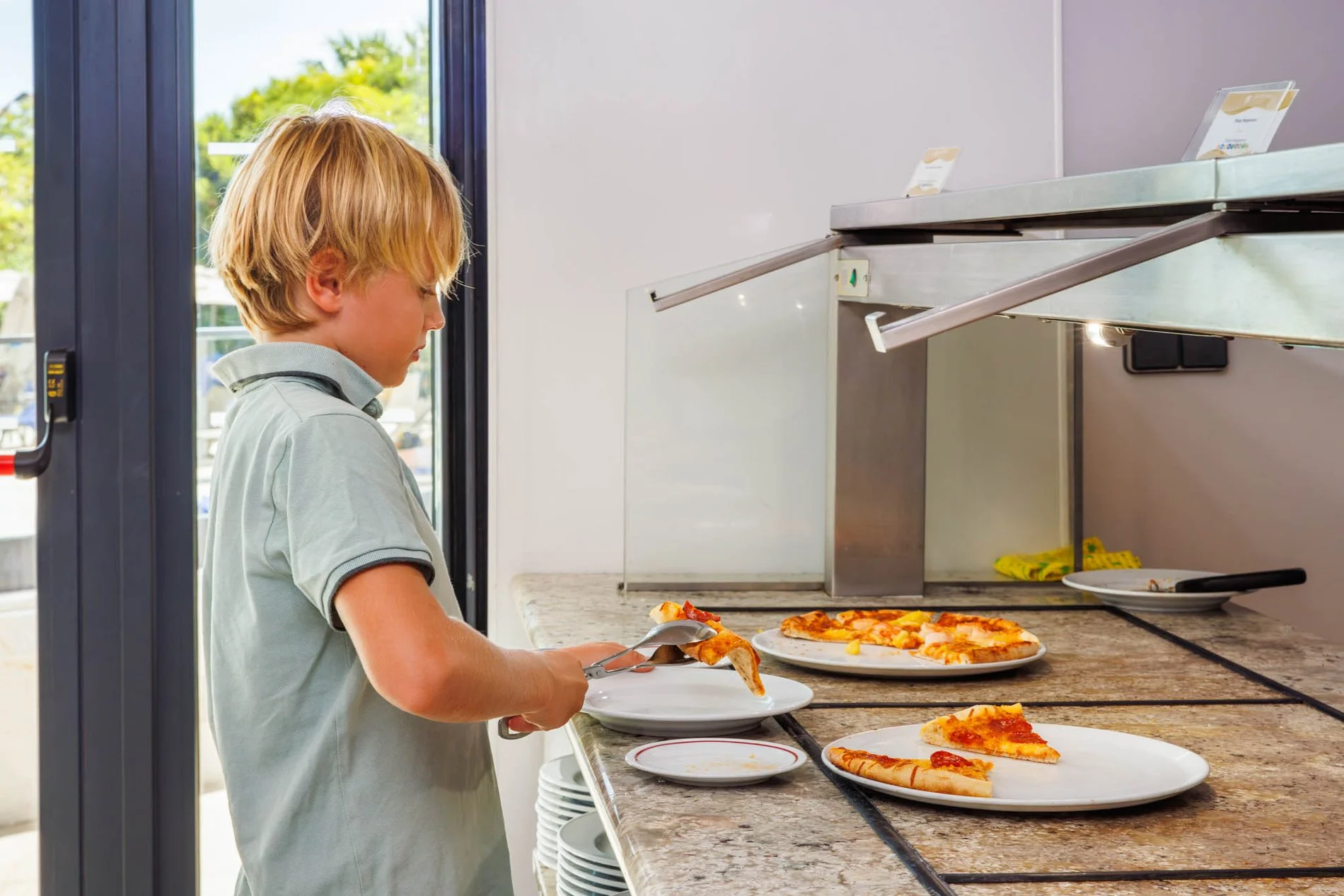 Enfant se servant différentes pizzas au restaurant Al Italiu de l’Hôtel Jupiter Albufeira