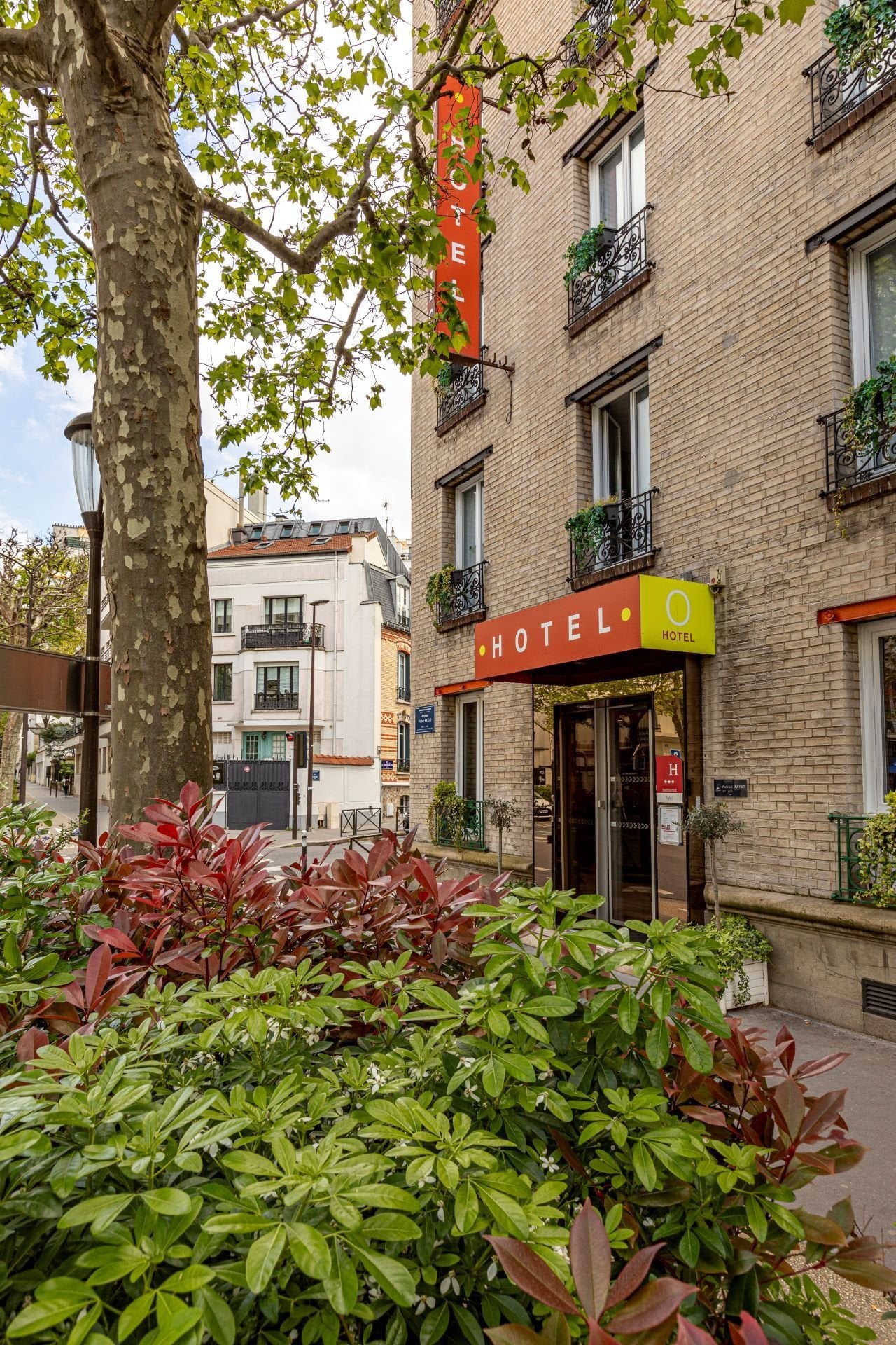 Entrée de l’Hôtel Olympic à Boulogne-Billancourt avec façade élégante, accès principal et environnement arboré aux portes de Paris.