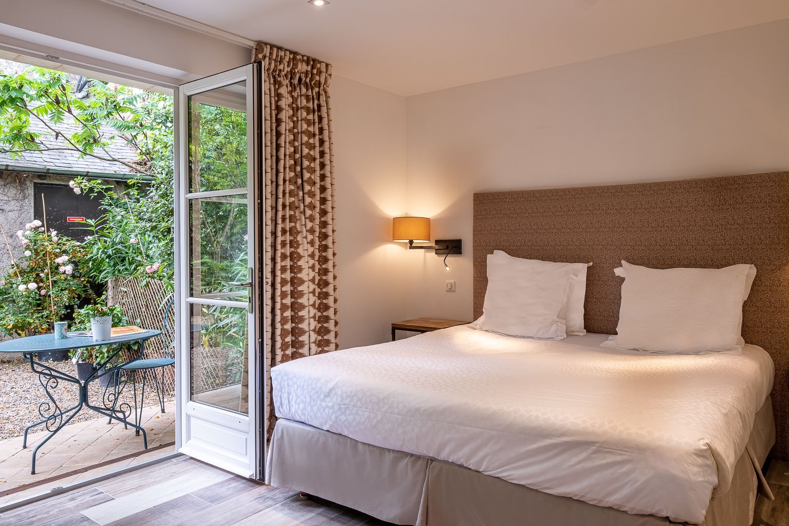 Chambre d'hôtel élégante avec lit double et vue sur un jardin à Chenonceaux