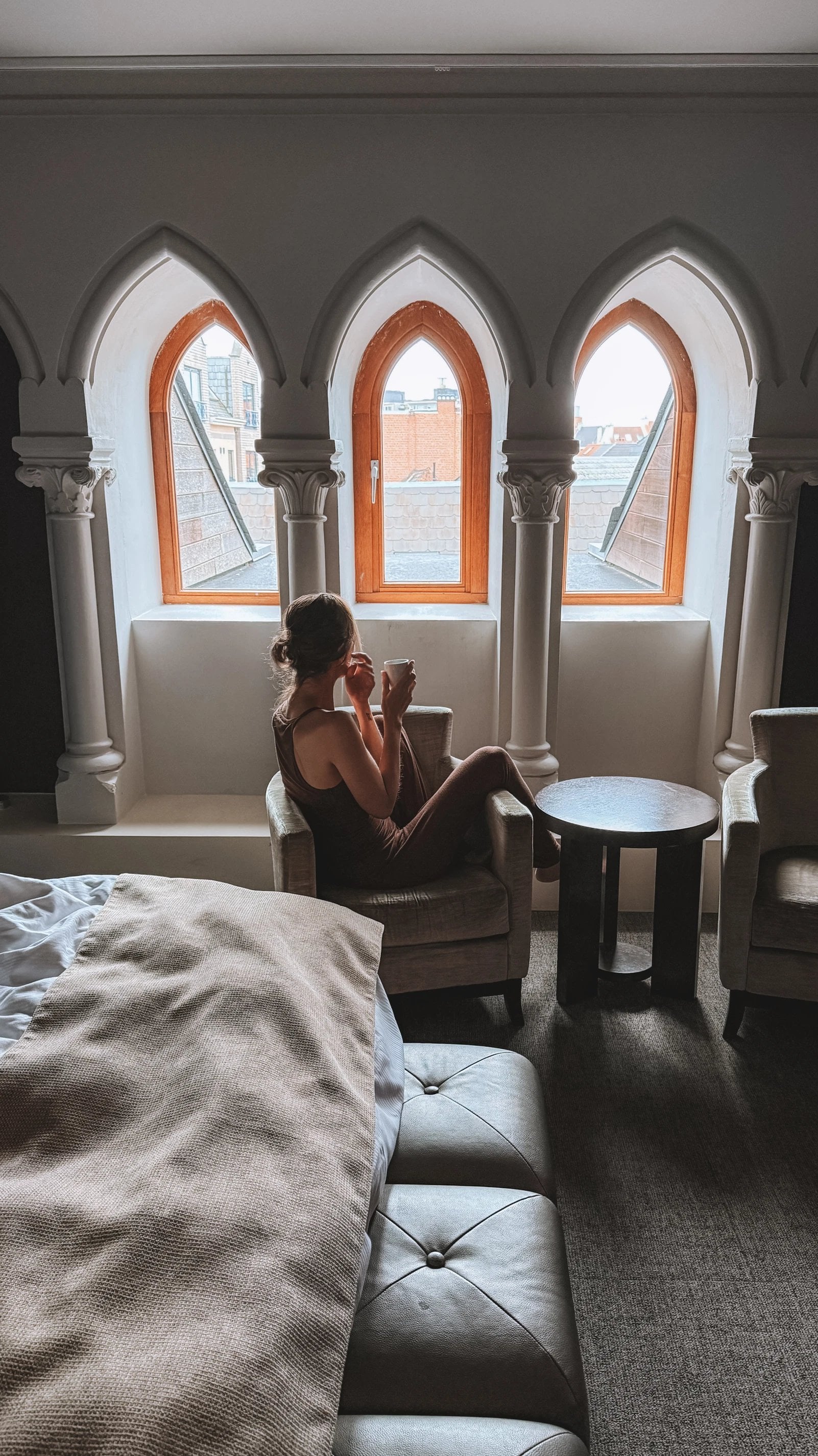 Chambre spacieuse avec lit à baldaquin et coin salon au Martin's Klooster à Louvain.