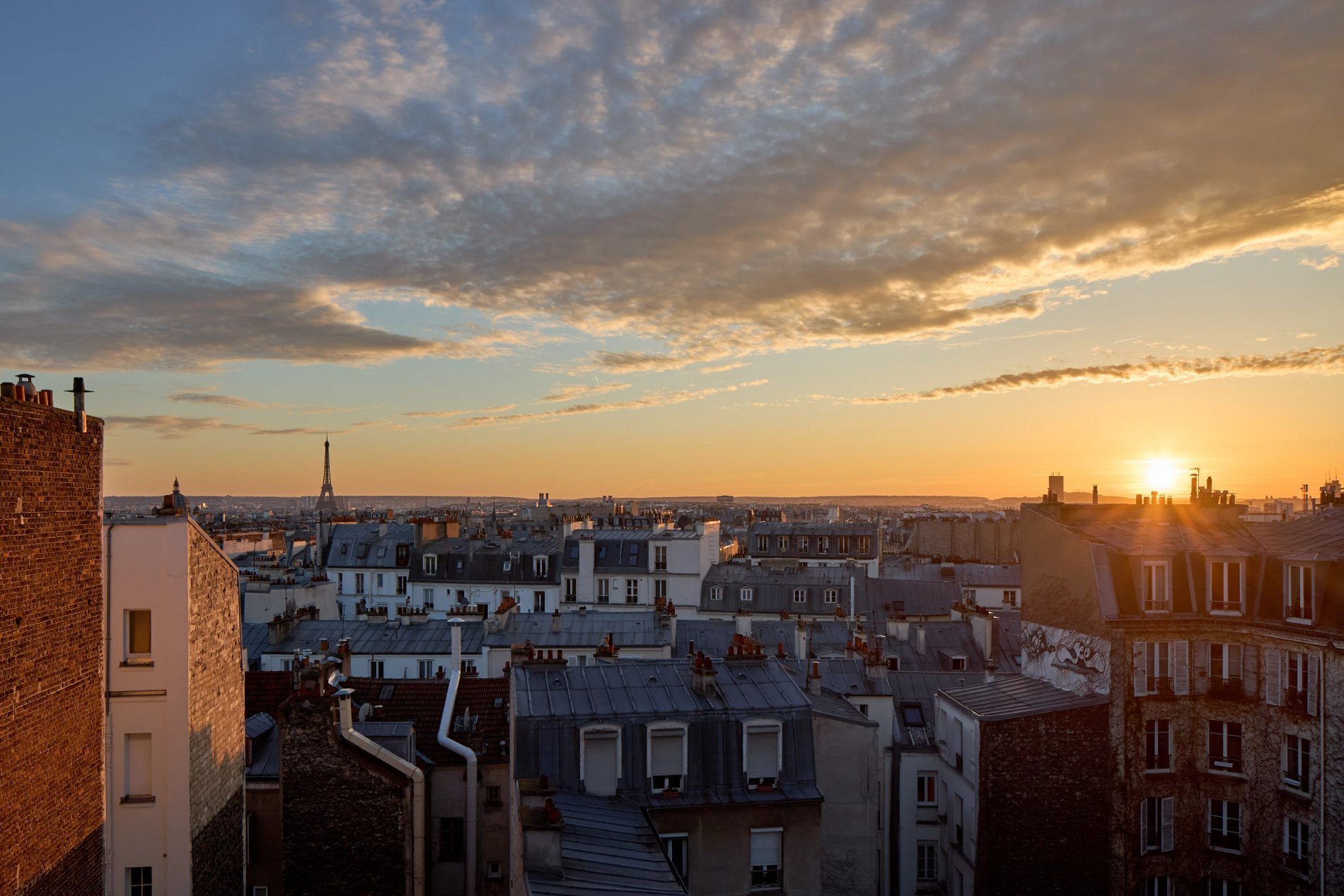 Vue au coucher de soleil sur les toits de Paris avec la Tour Eiffel à l’horizon depuis Maison Cassandre