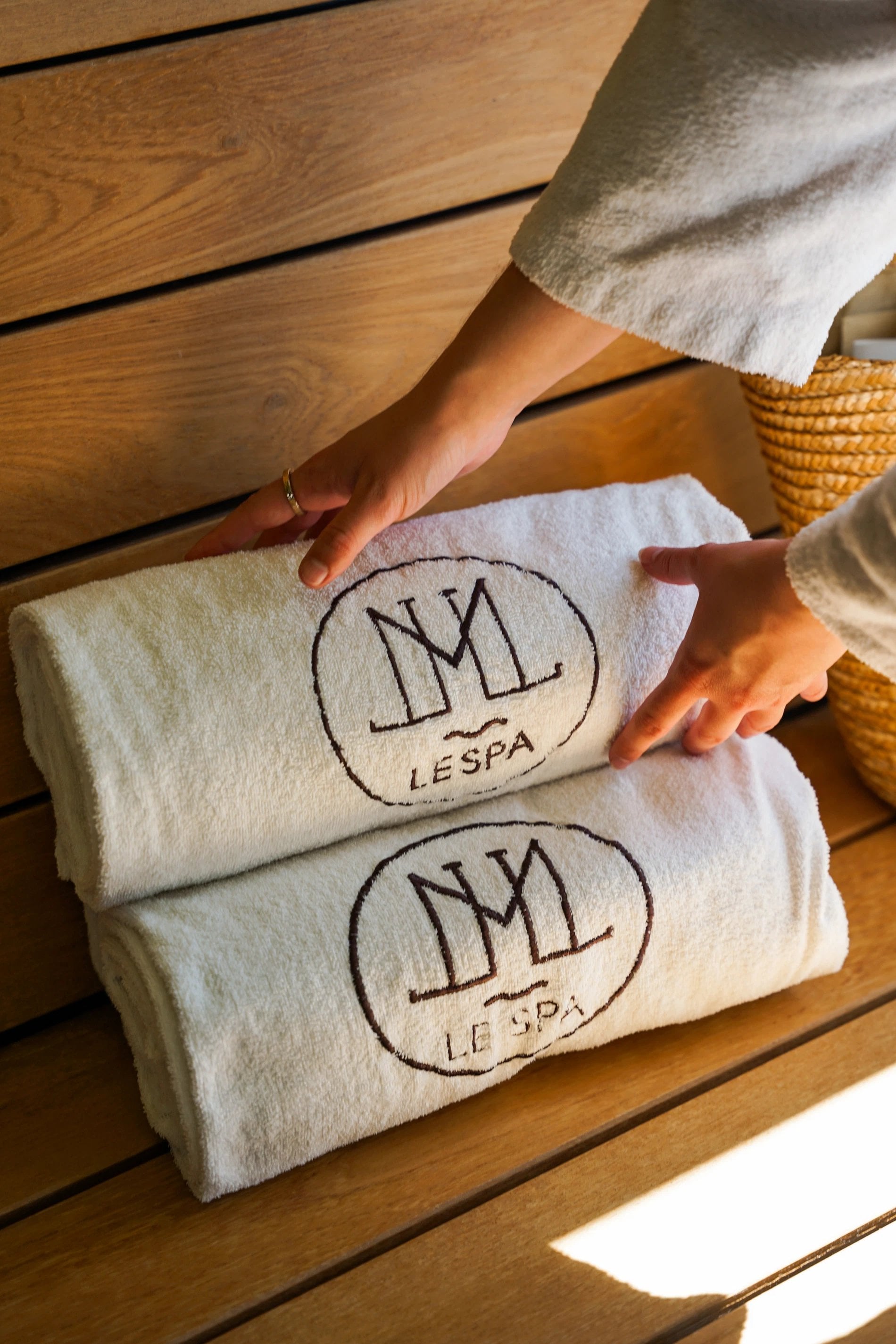 Folded spa towels with the La Côte Saint Jacques logo placed on a wooden bench
