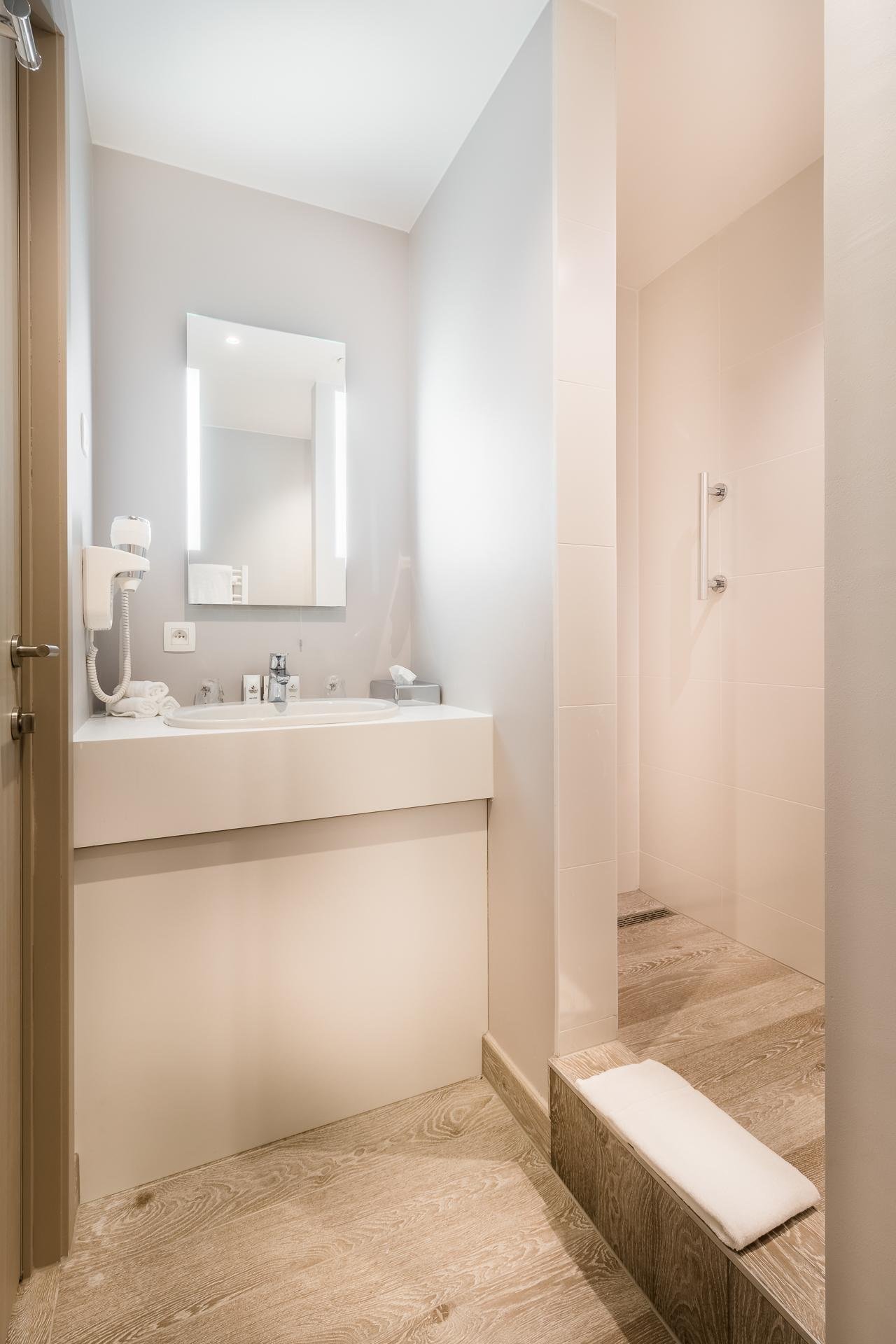 Modern bathroom at Martin's Red with a lighted mirror and a shower cabin.