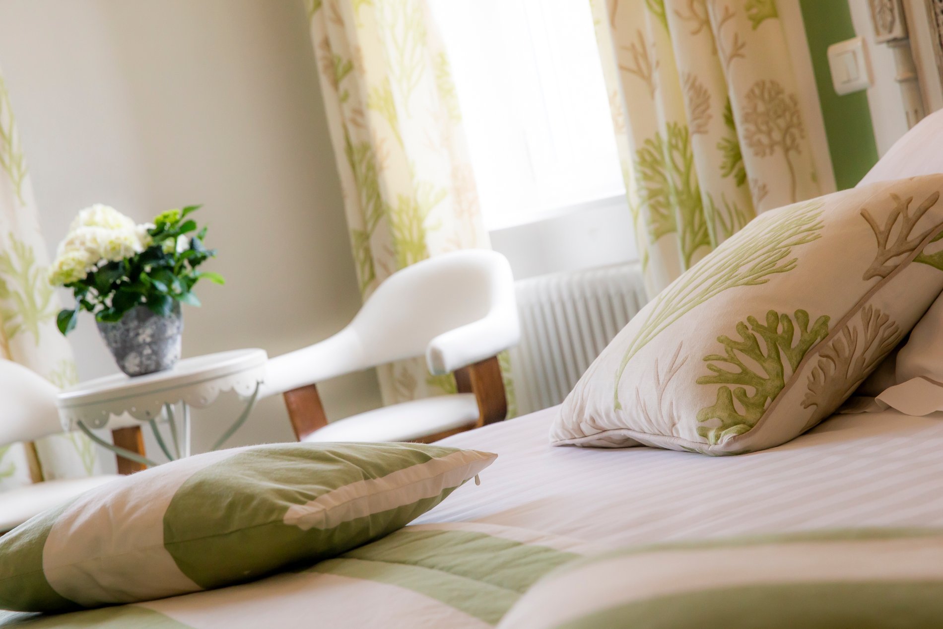 Hotel La Ramade's 'Ville de Ramade' room with canopy bed and green striped decor, symbolizing a unique and elegant style