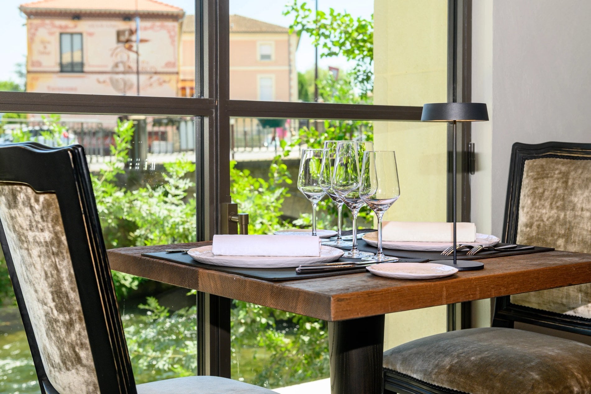 Table dressée au restaurant La Roue avec vue sur la végétation à L’Isle de Leos.