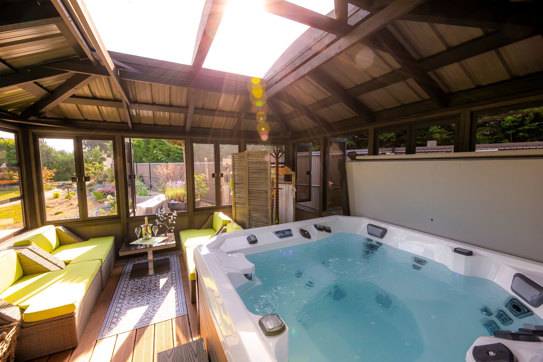 Jacuzzi couvert sous un toit vitré à l'Hôtel La Ramade, symbolisant un espace de détente abrité.