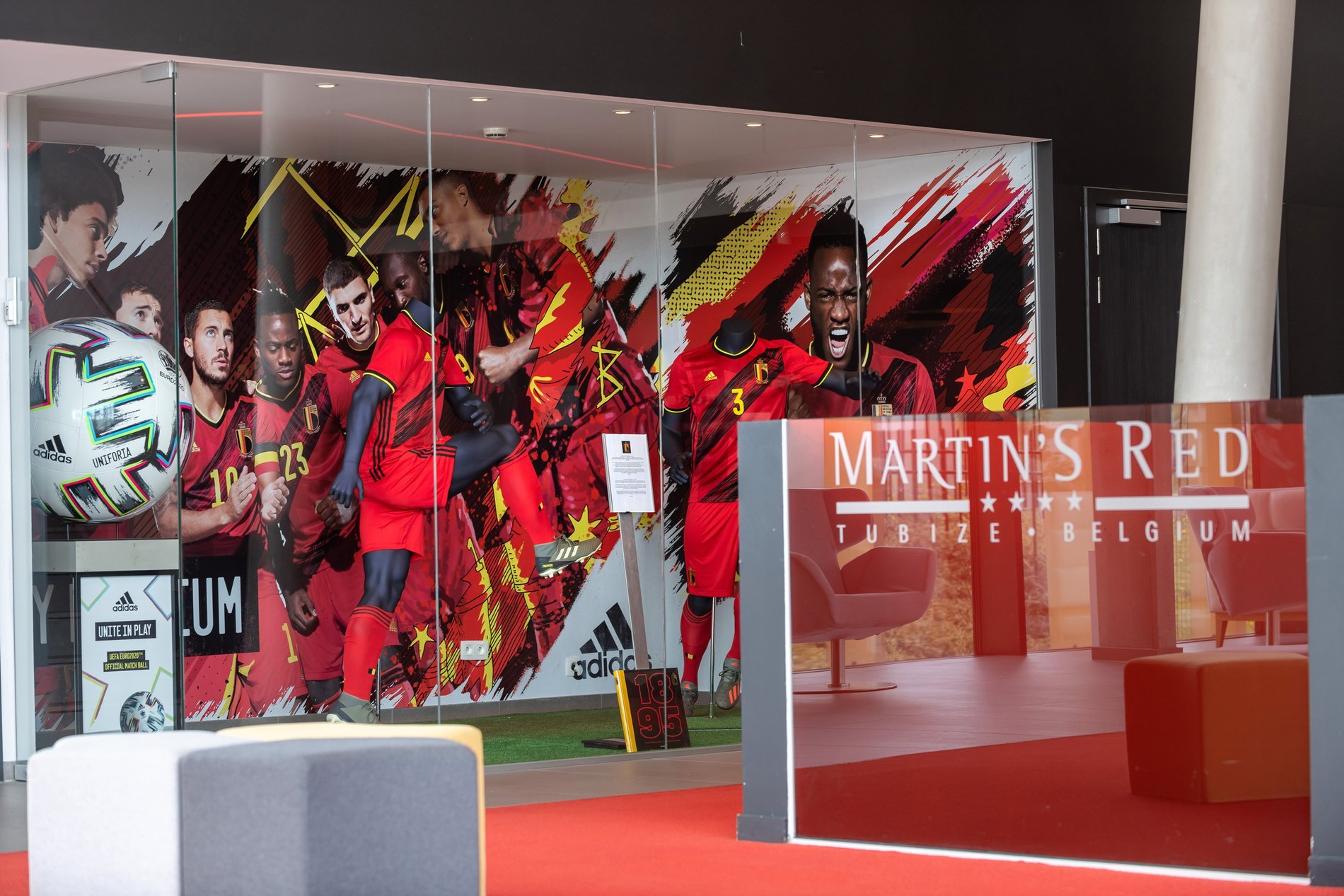 Winkel met sportuitrusting en rode kleding tentoongesteld op moderne rekken.