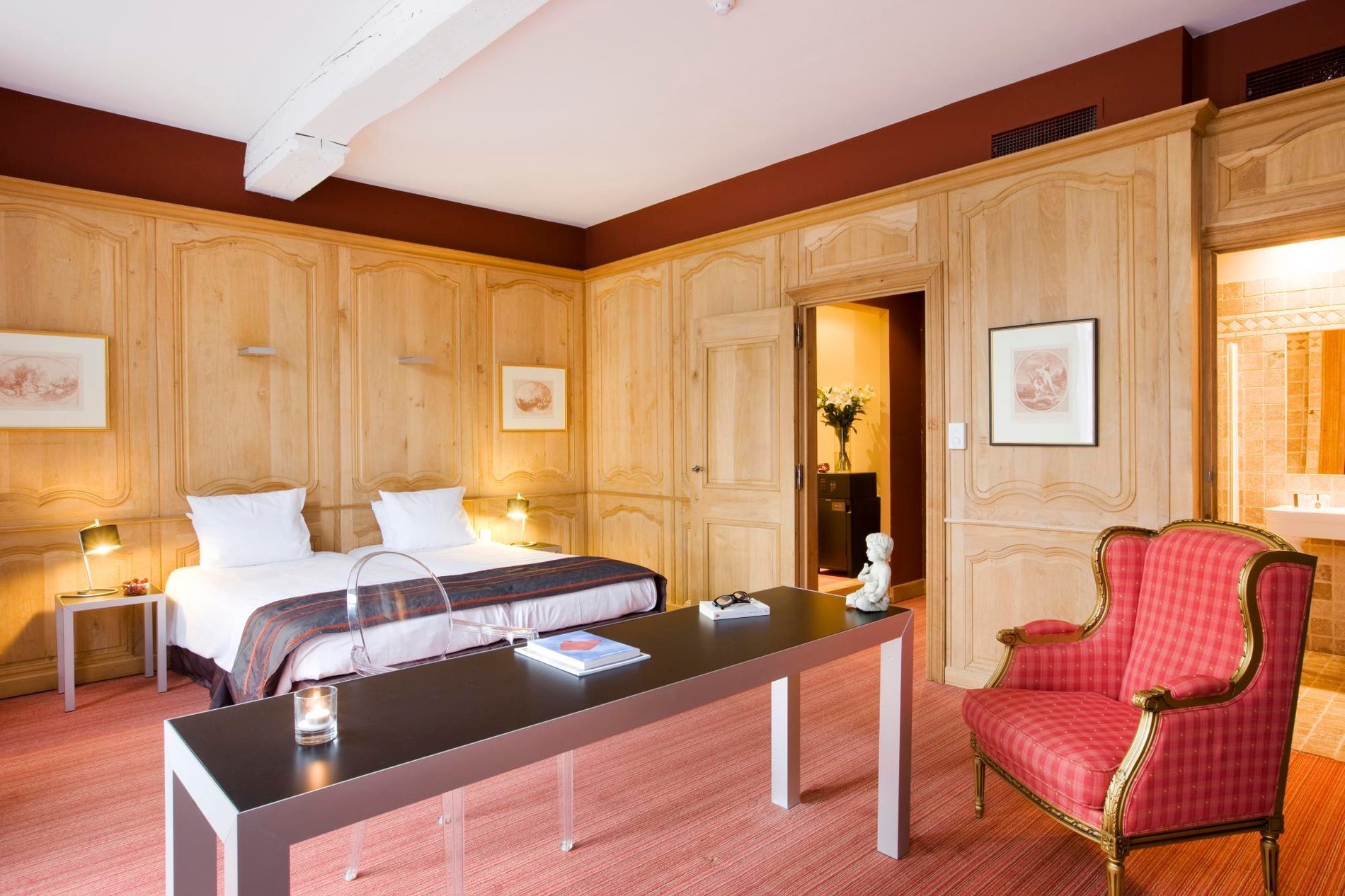 Chambre élégante avec des panneaux en bois et un fauteuil rouge à Martin’s Relais.