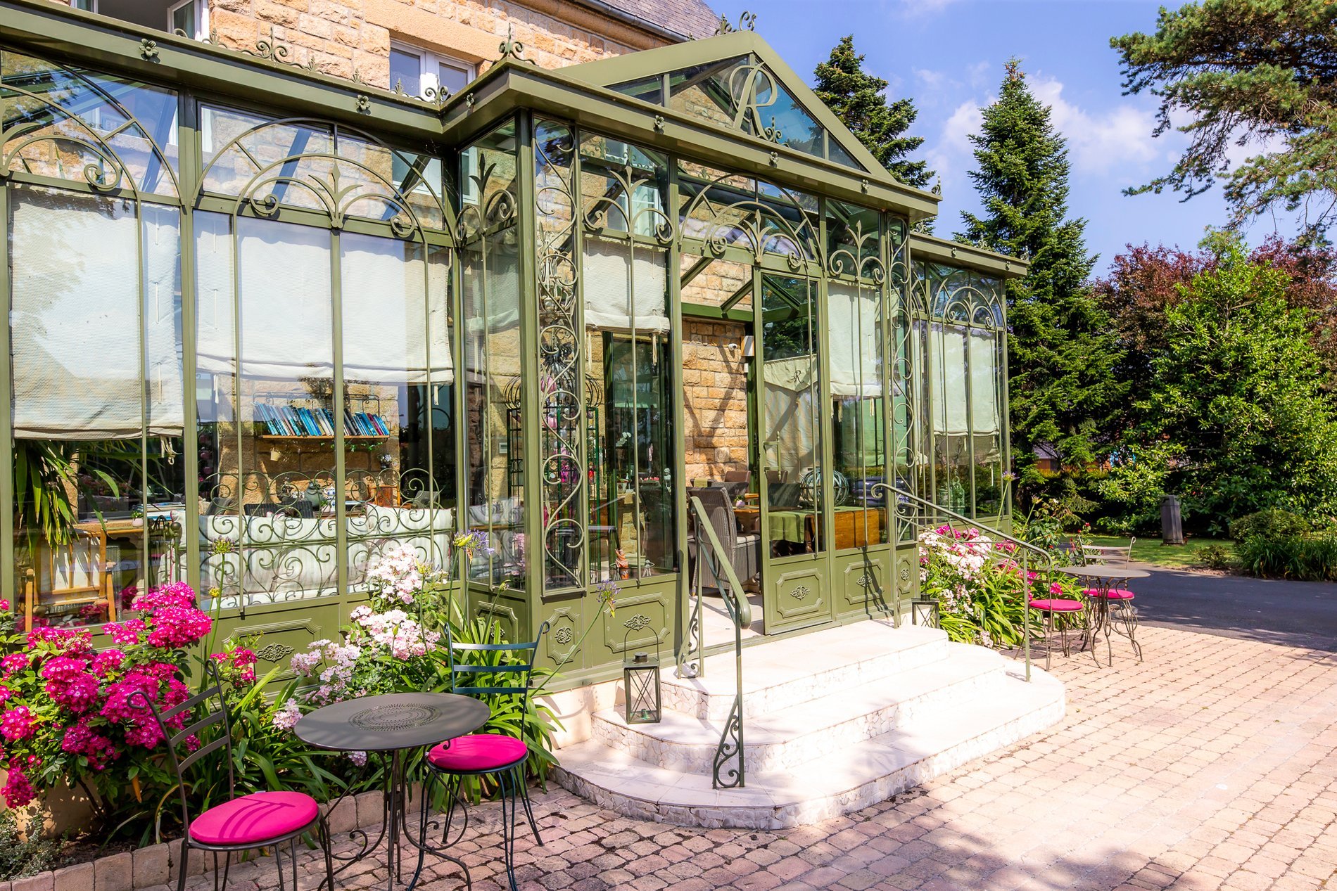 Véranda de l'Hôtel La Ramade avec jardin et mobilier extérieur, symbolisant un espace lumineux et aménagé pour la détente.