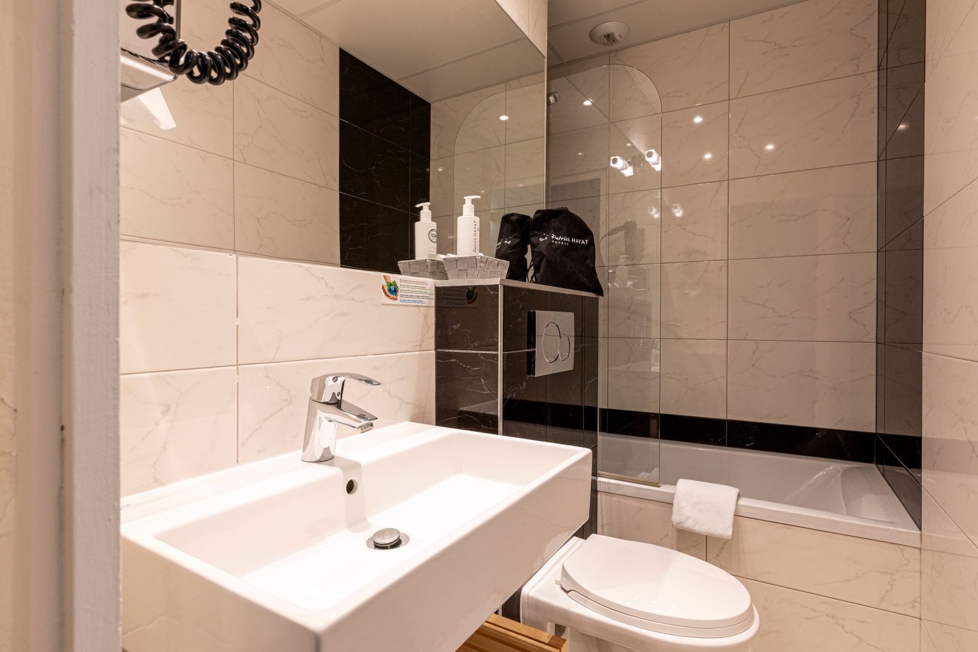 Salle de bain privative de la Chambre Classique Double Olympic à Boulogne-Billancourt avec baignoire, lavabo moderne et équipements de confort.
