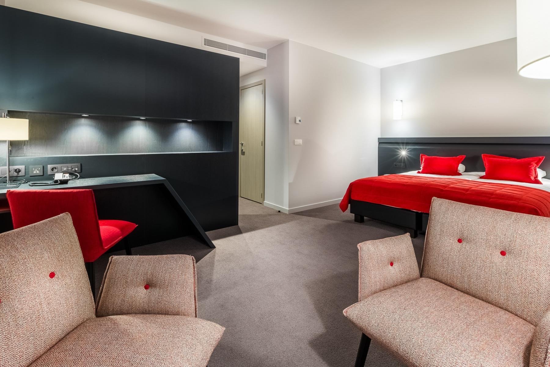 Chambre spacieuse avec espace salon et touches de rouge