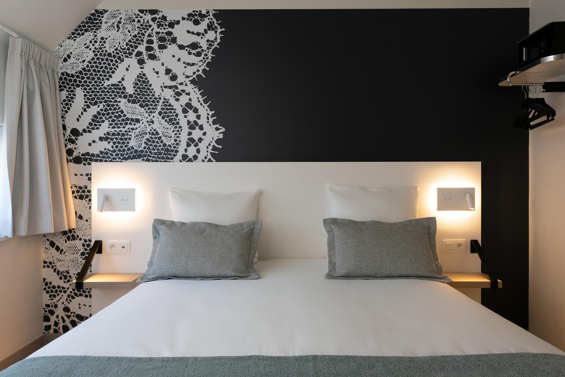 Bequemes Doppelbett mit schwarz-weißer Wanddekoration im Martin's Brugge