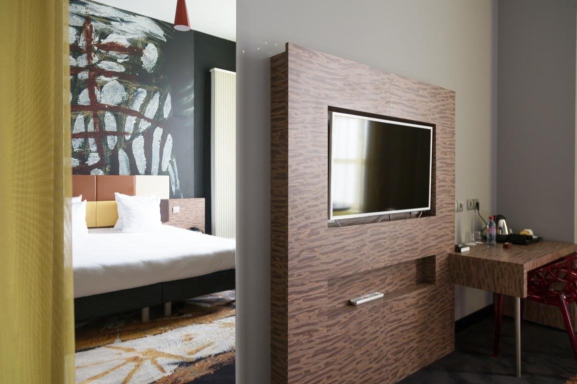 Gemütliches Zimmer mit Doppelbett und Wandfernseher.