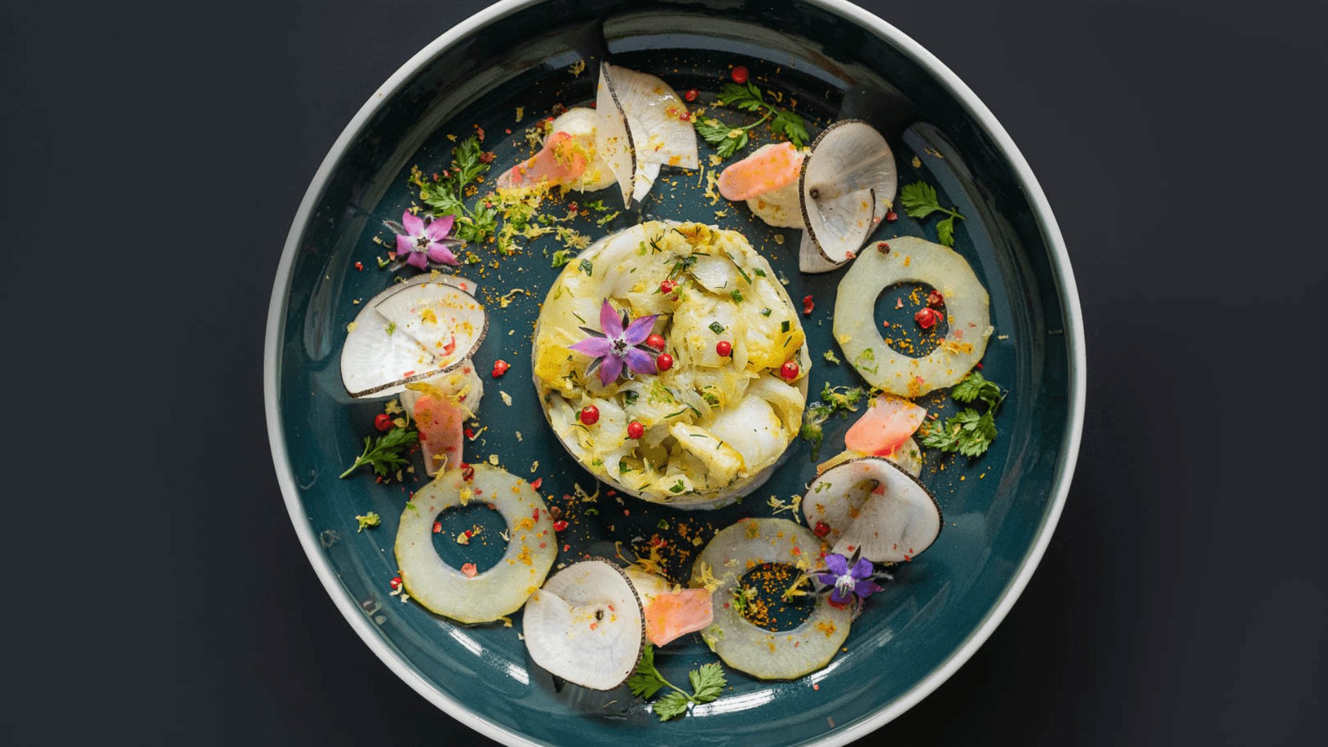 A beautifully decorated gourmet dish with vegetables and edible flowers.