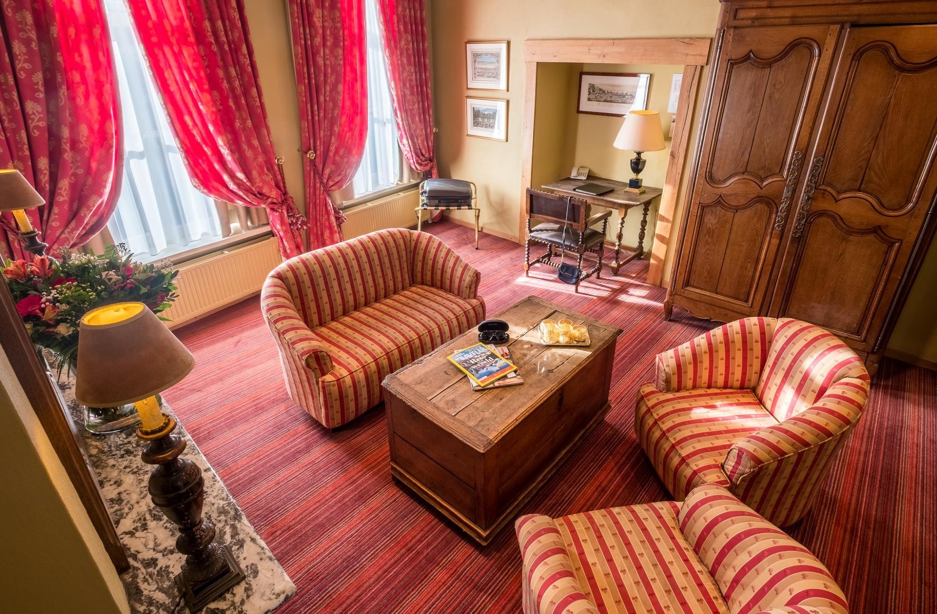 Coin salon chaleureux avec fauteuils et rideaux rouges à Martin’s Relais.