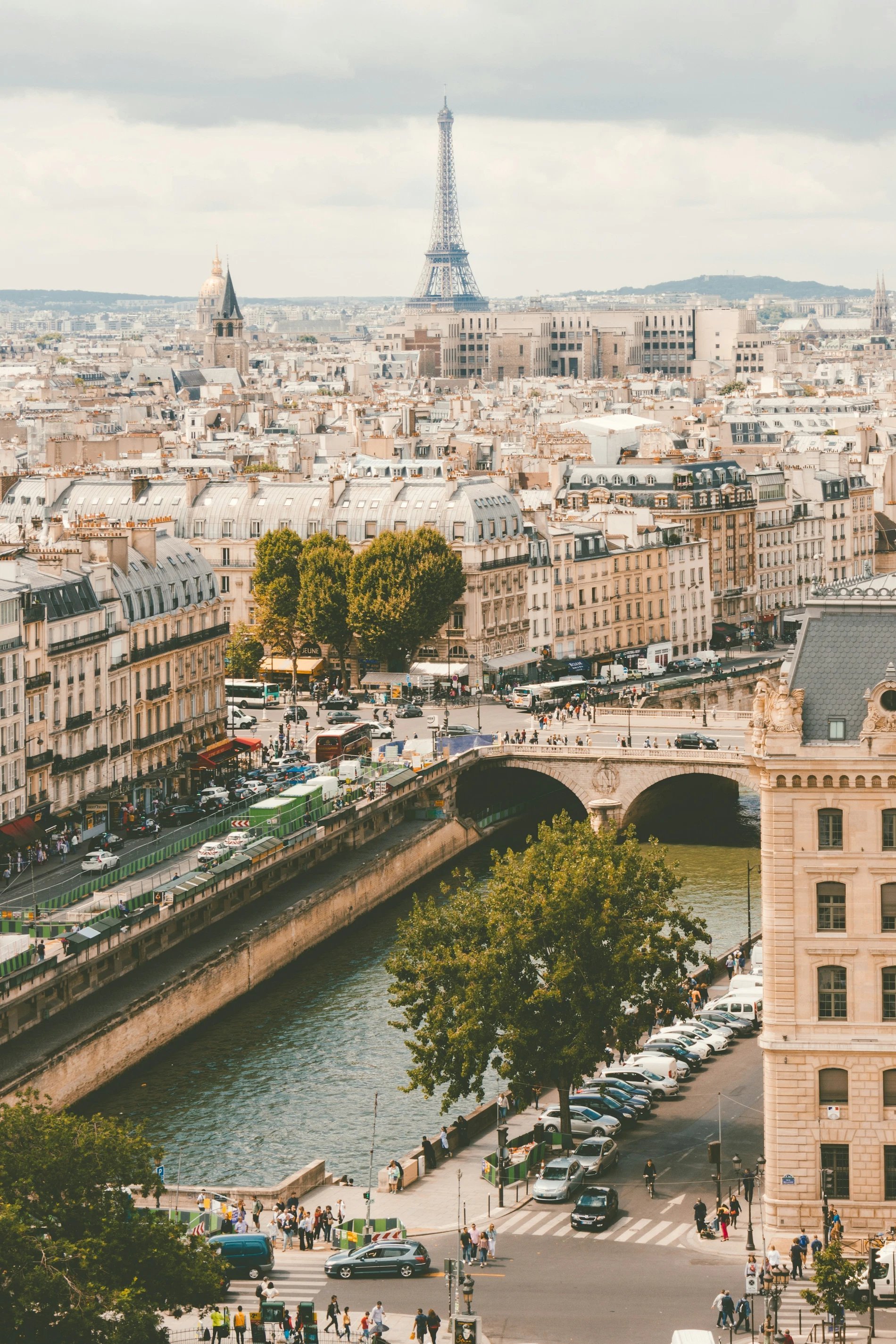 Une vue panoramique sur les toits de Paris avec la Tour Eiffel, illuminée par les lumières de la ville la nuit, représentant une visite à Paris.