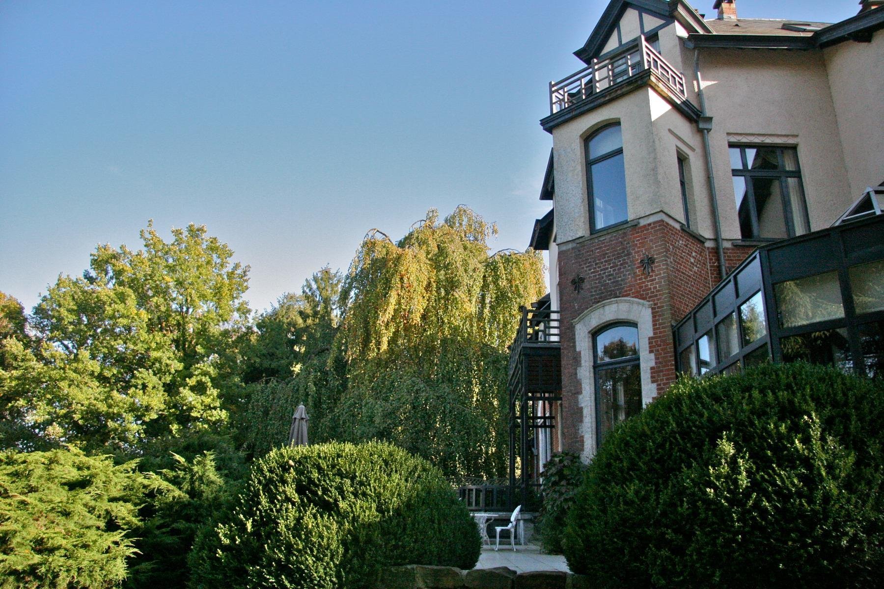 Façade élégante du Manoir de Genval entourée de verdure.