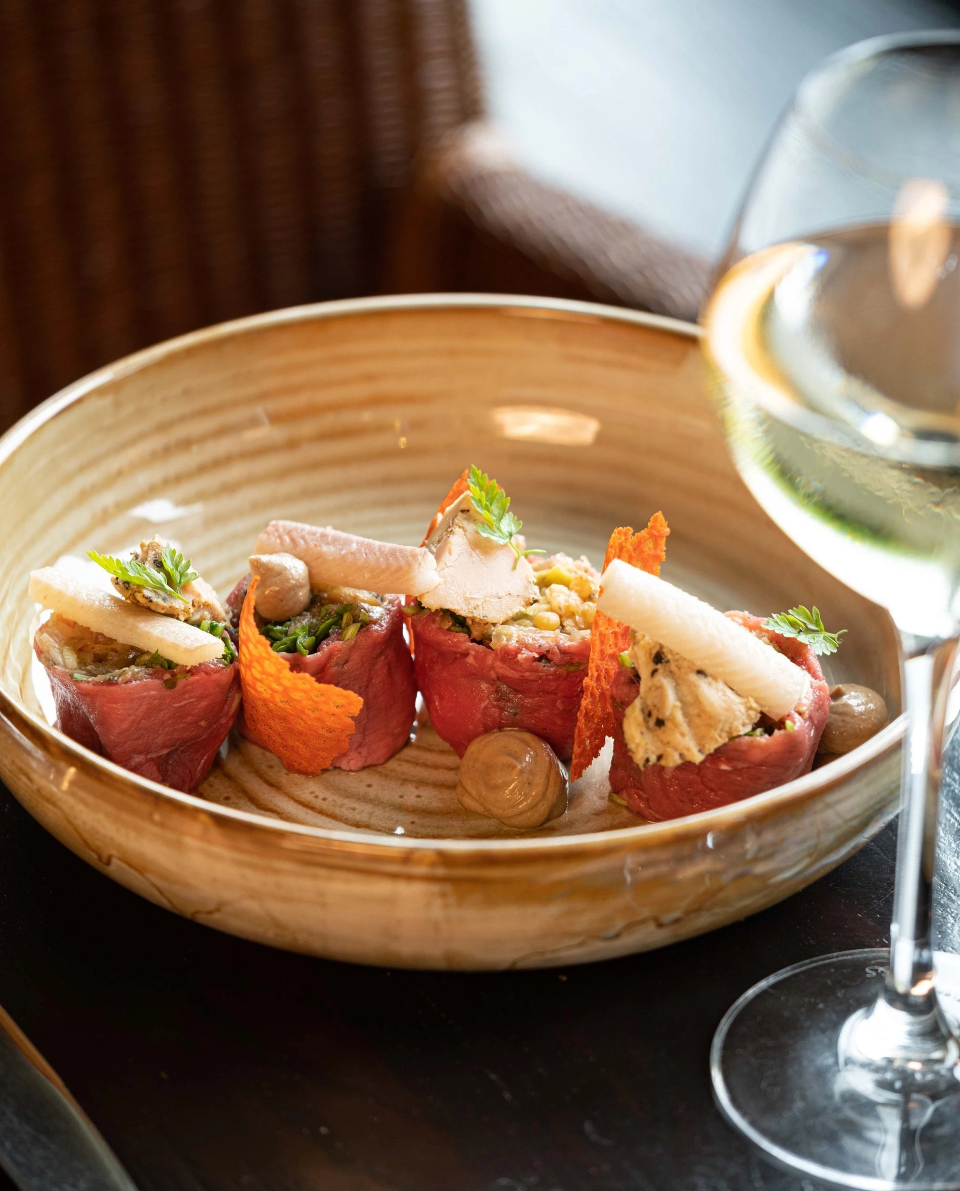 Plate of colorful tapas served with a glass of white wine.