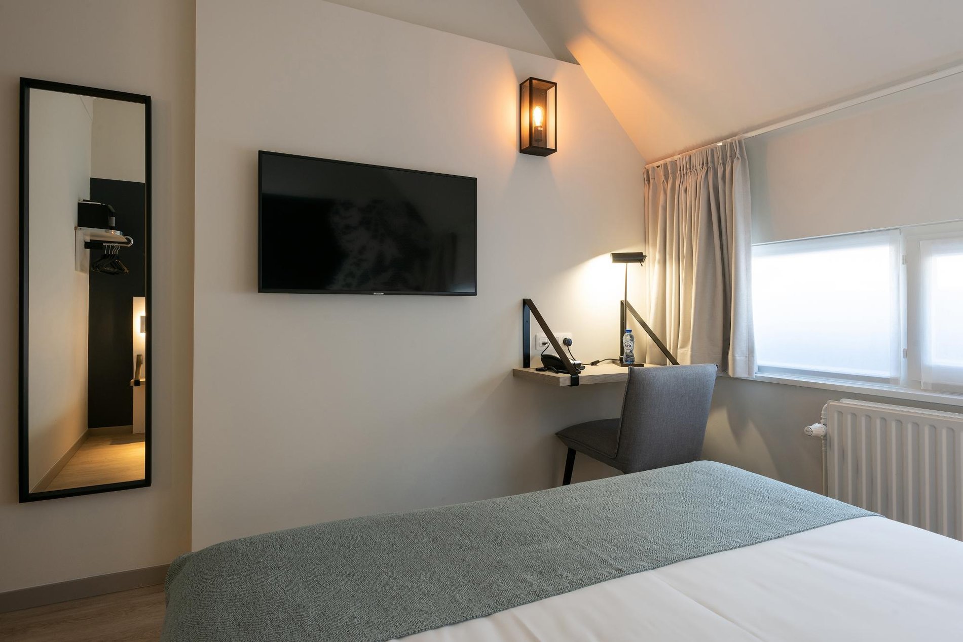 Entspannungsbereich mit Spiegel und Sessel in einem Zimmer im Martin's Brugge