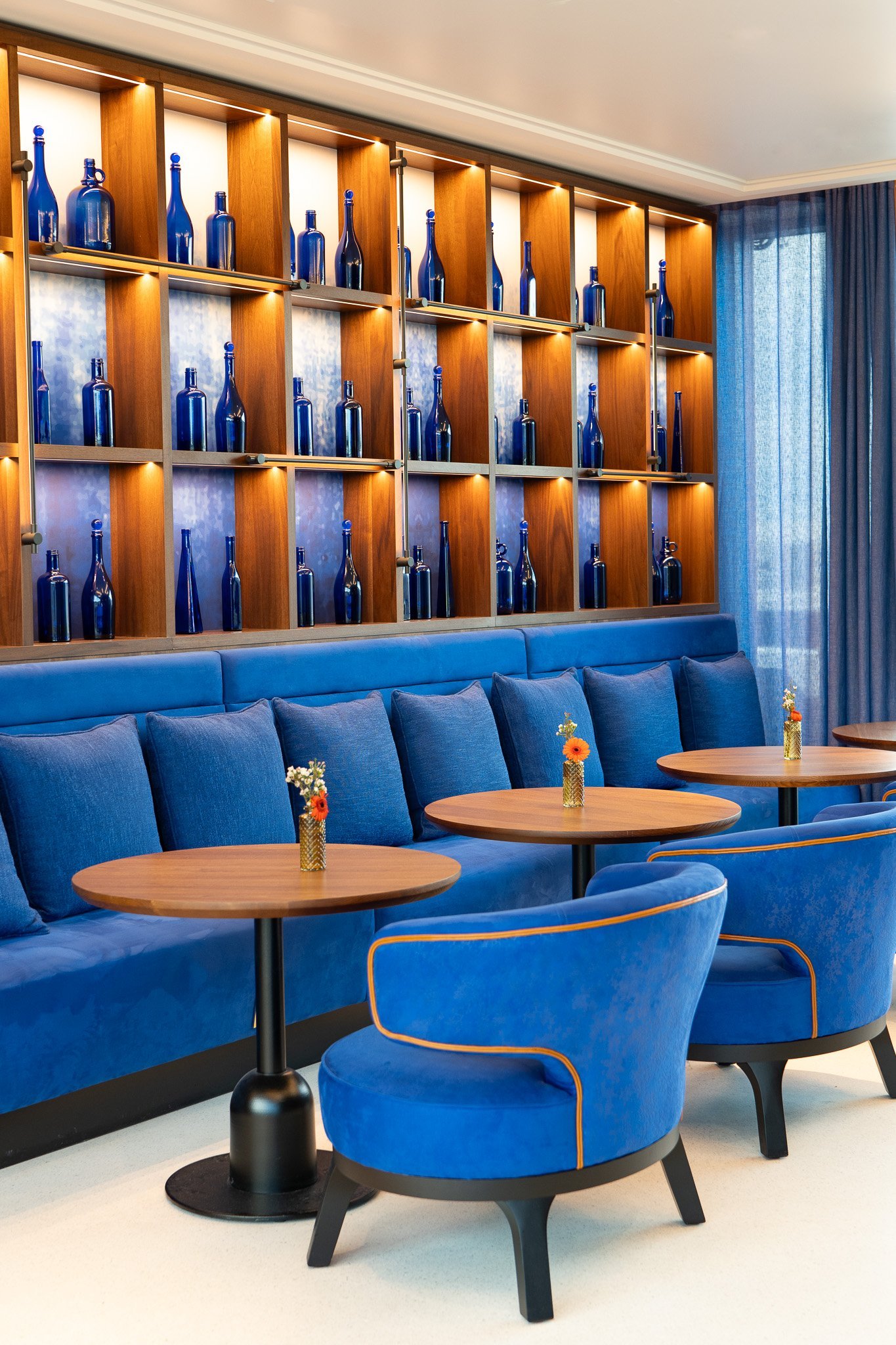 Bar bleu marine : étagères de bouteilles, fauteuils cosy, tables.