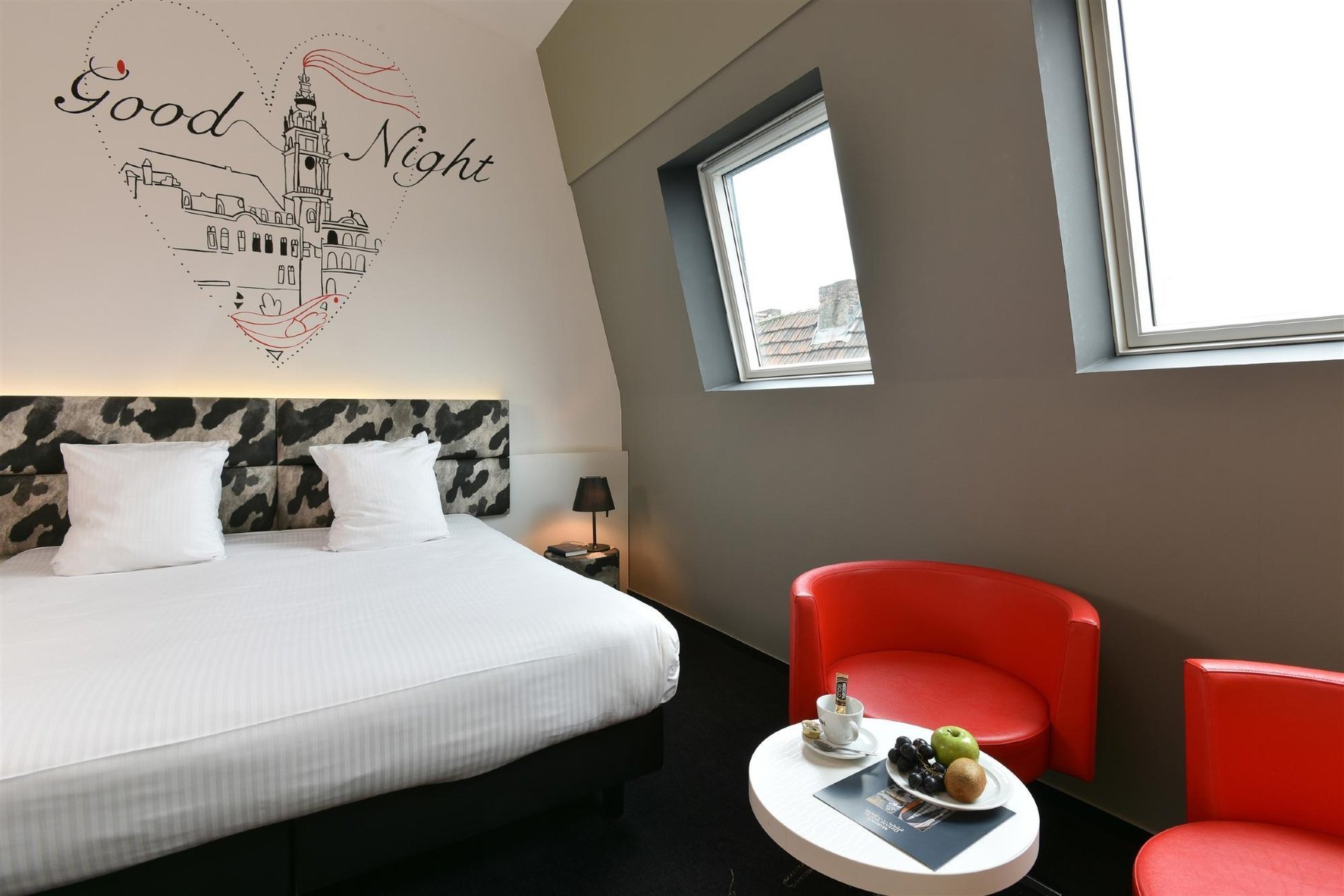 Gemütliches Plus-Zimmer mit roten Stühlen und Doppelbett.