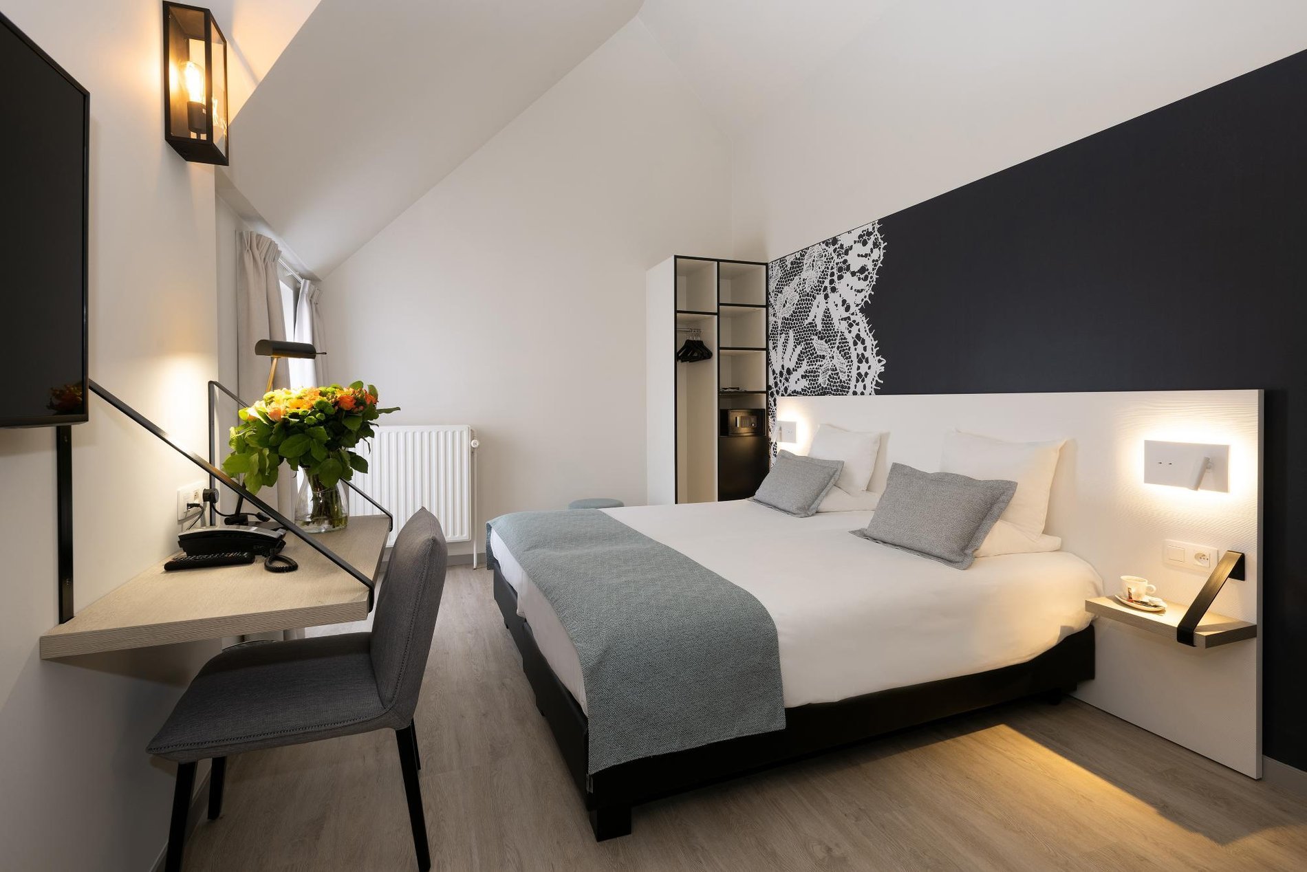 Arbeitsbereich und Doppelbett in einem hellen Zimmer im Martin's Brugge