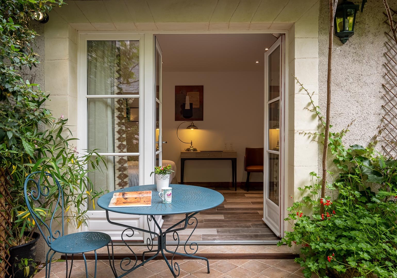 Terrasse avec table et chaise en métal devant une porte-fenêtre ouverte