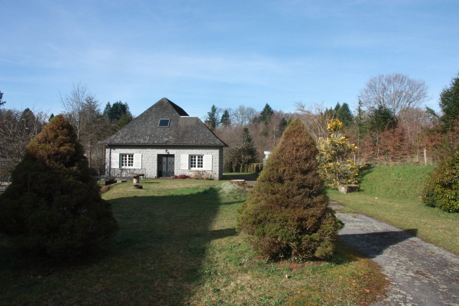 Vue lattérale de Villa Corrèze Aventure, entourée de conifères.