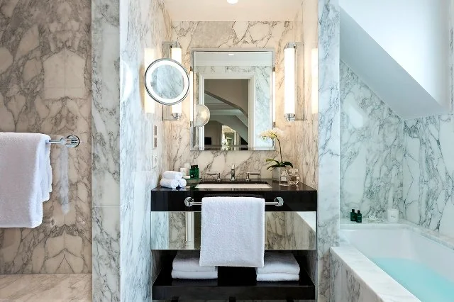 Salle de bain Prestige de l’Hôtel San Régis avec baignoire sous mansarde et marbre raffiné.