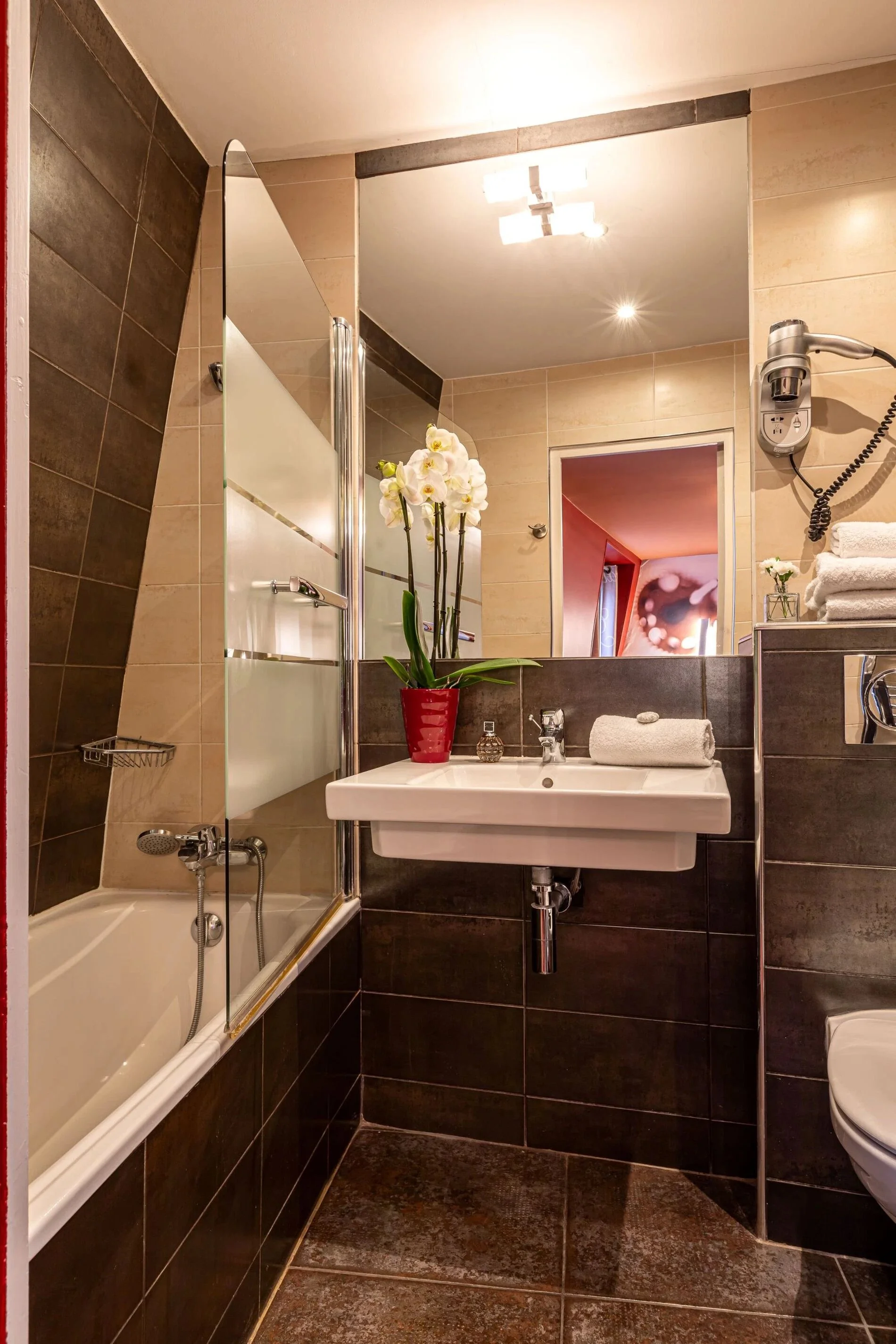 Salle de bain privative de la Chambre Triple avec baignoire, sèche-cheveux et produits d'accueil à l'Hôtel Ariane Montparnasse