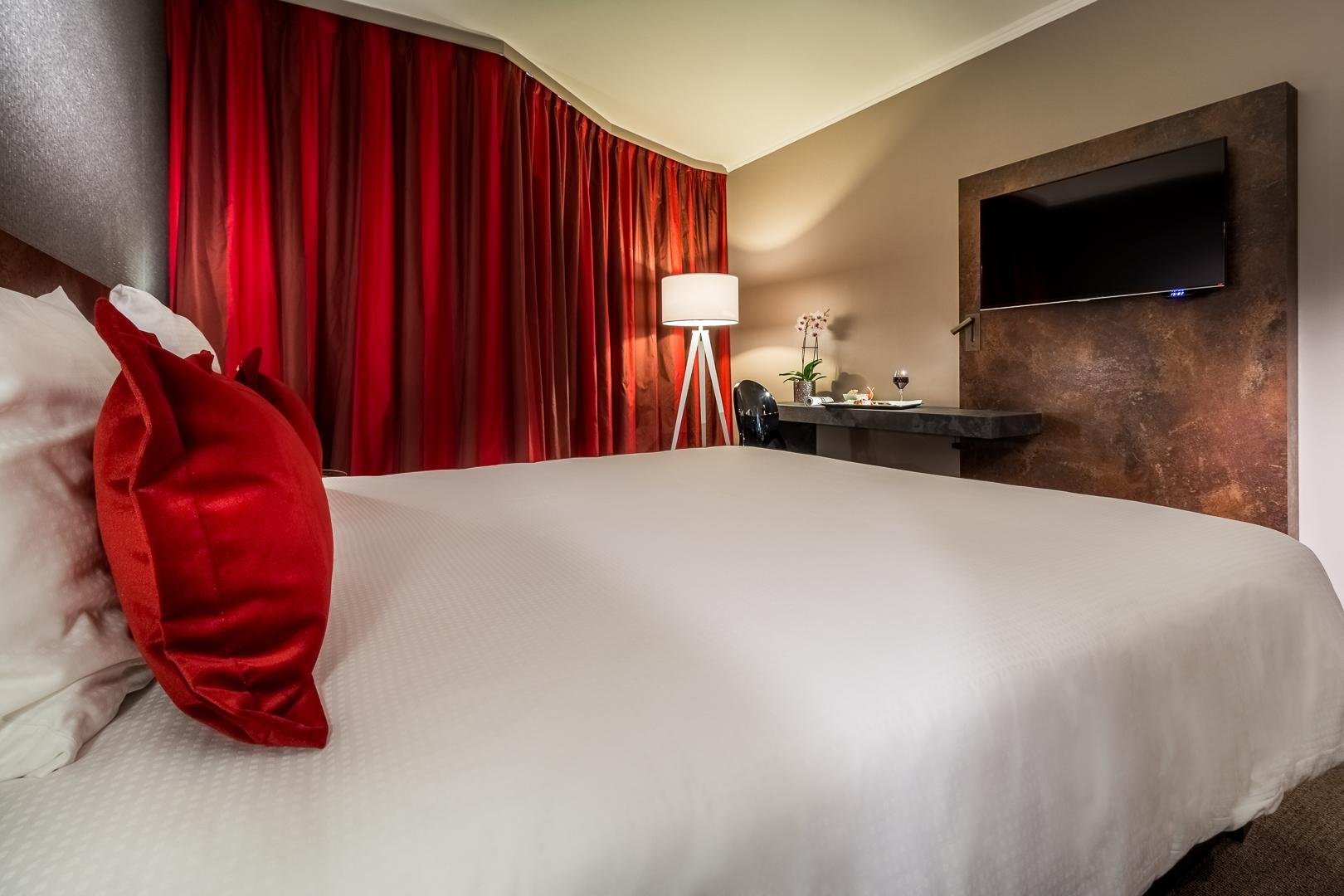 Comfortable bed with red curtains and soft lighting