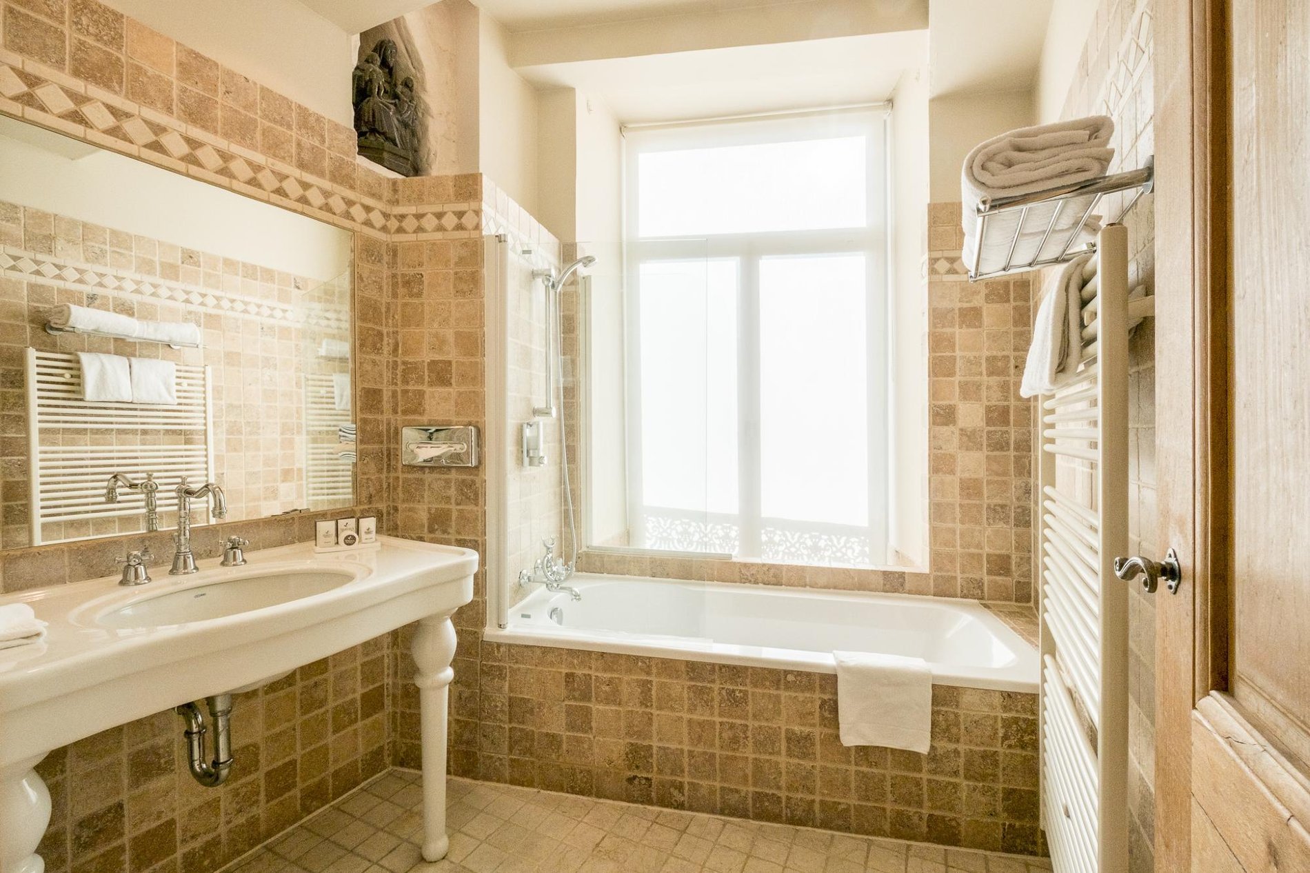 Salle de bain lumineuse avec baignoire et carrelage beige à Martin’s Relais.