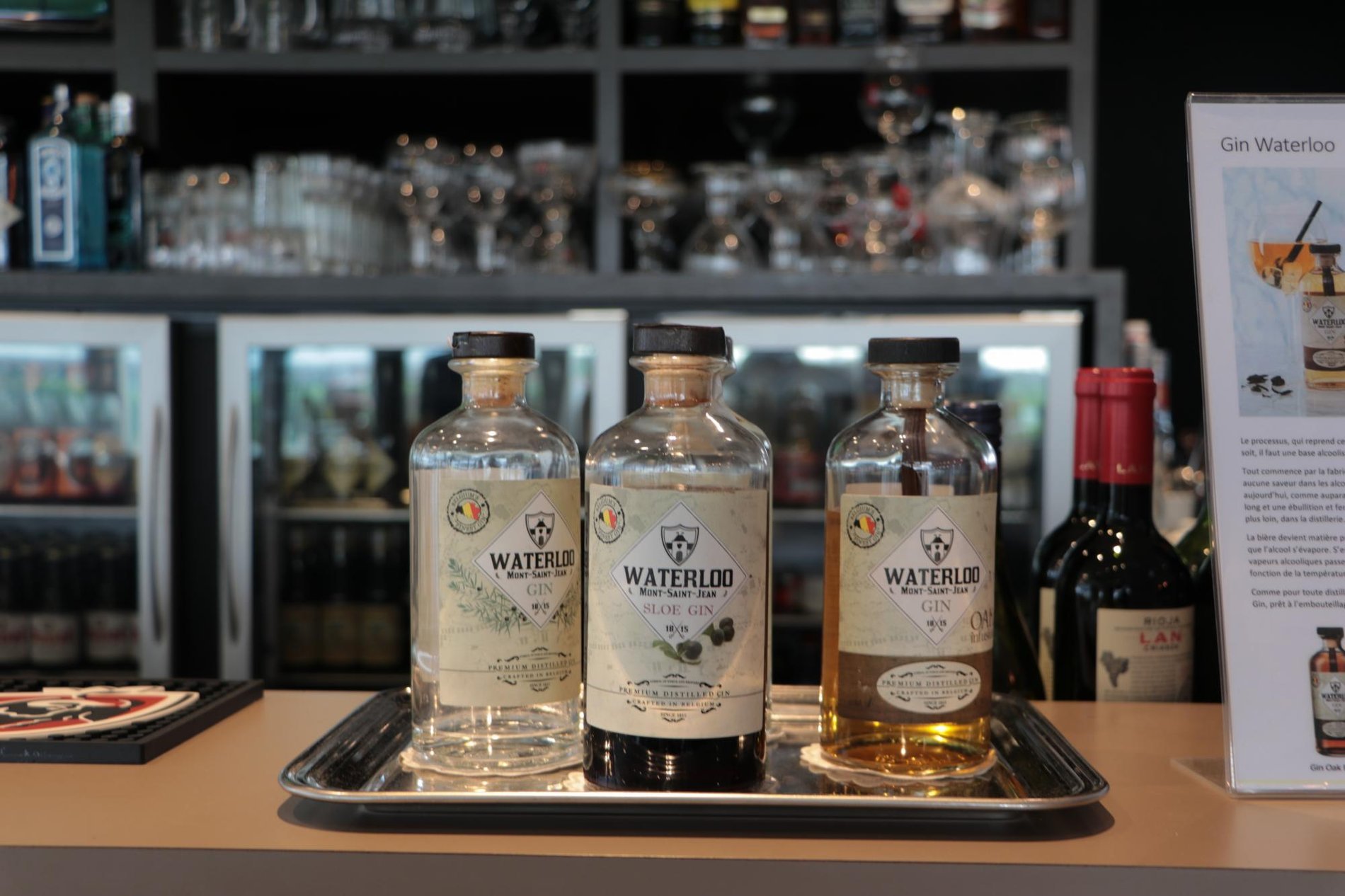 Shelf filled with bottles of spirits and glasses, in an elegant bar setting.